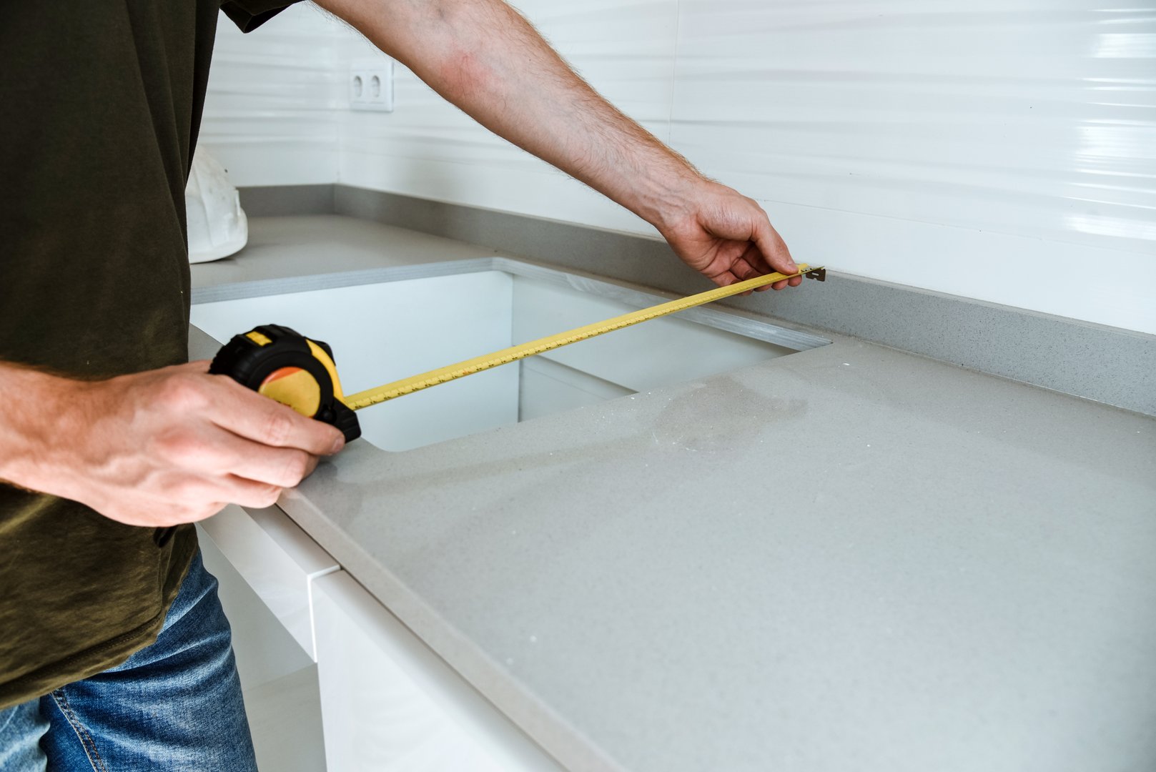 Detail of a man measuring the gap in a kitchen cabinet. Concept of custom furniture installation in a new flat. Hollow for a ceramic hob.