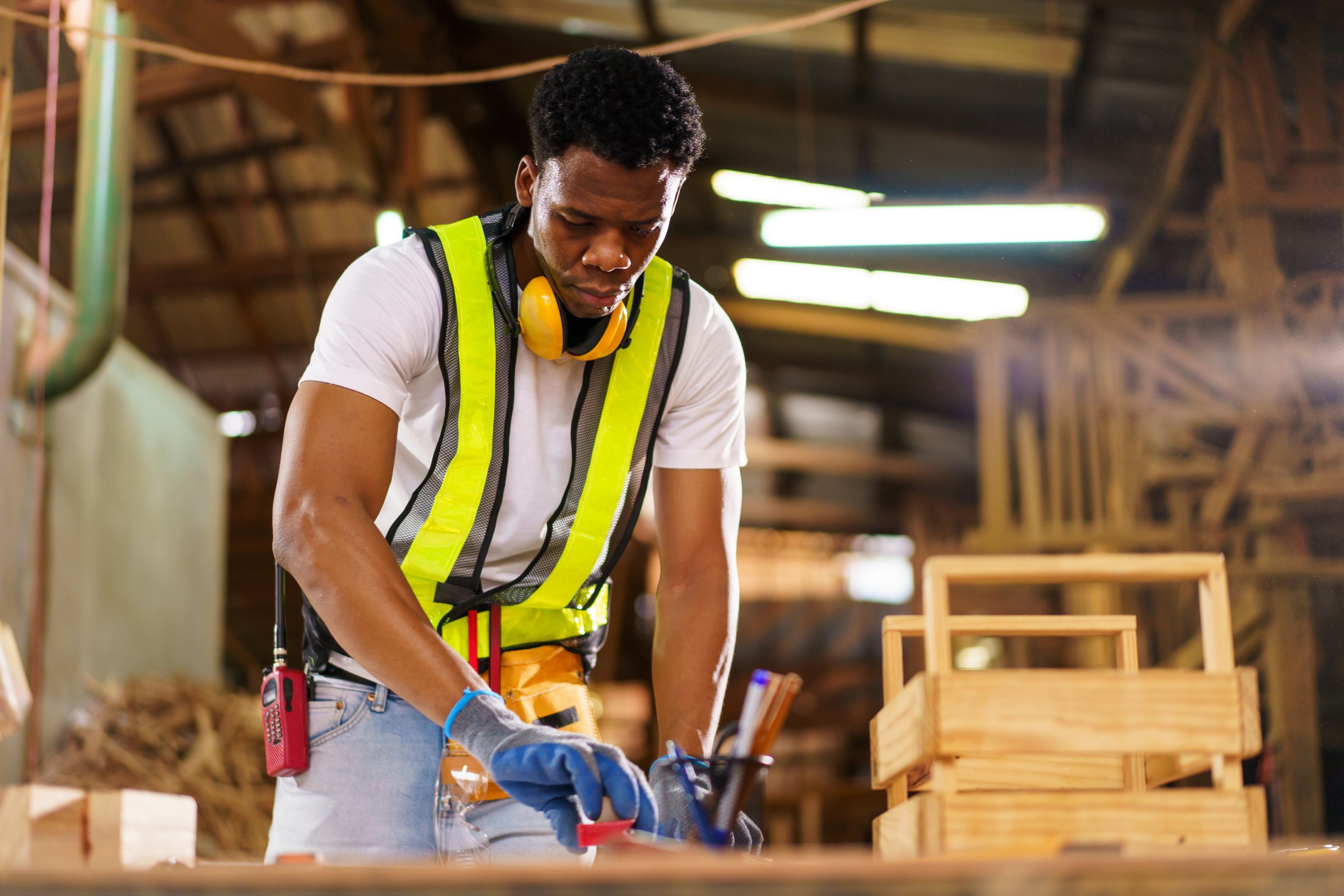 An African carpenter in a woodworking workshop carefully inspecting a sawn wooden plank with focus and precision. Represents craftsmanship, manual labor, skill, industry, craftsmanship and profession.