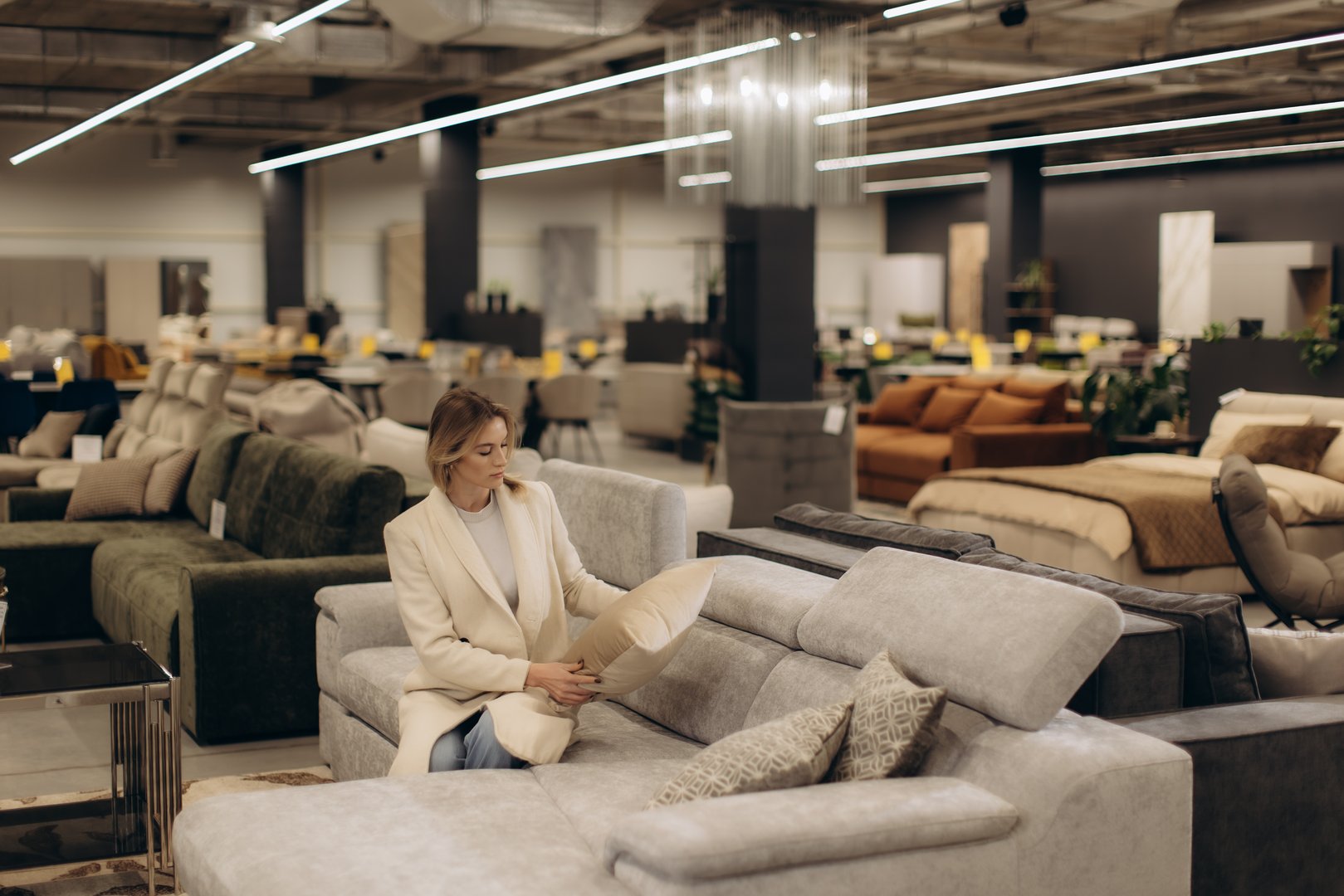 A stylish woman examines a sofa in a well-lit, modern furniture store