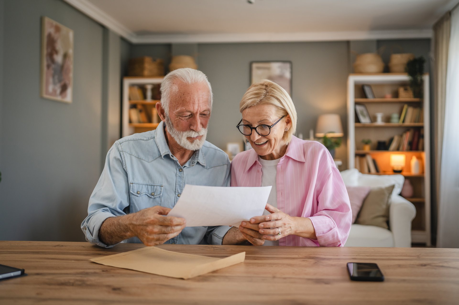 Senior couple read a letter document from envelope together at home