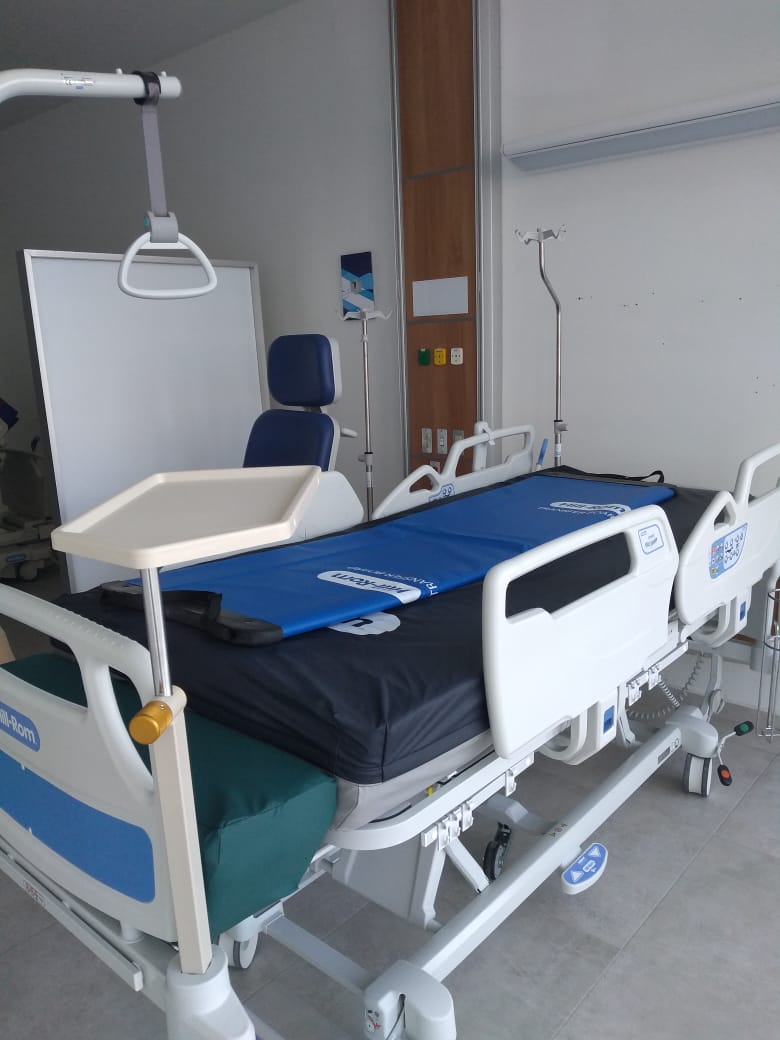 Hospital room with an adjustable bed, medical equipment, and an empty IV stand.