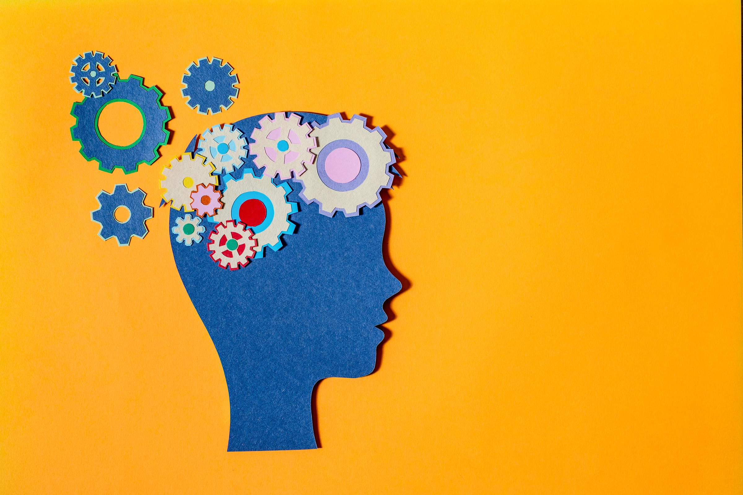 Paper cut-out head displaying gears symbolizing mental health and thought