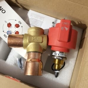 Brass valve and red gas regulator in a cardboard box with instructions and packing material.