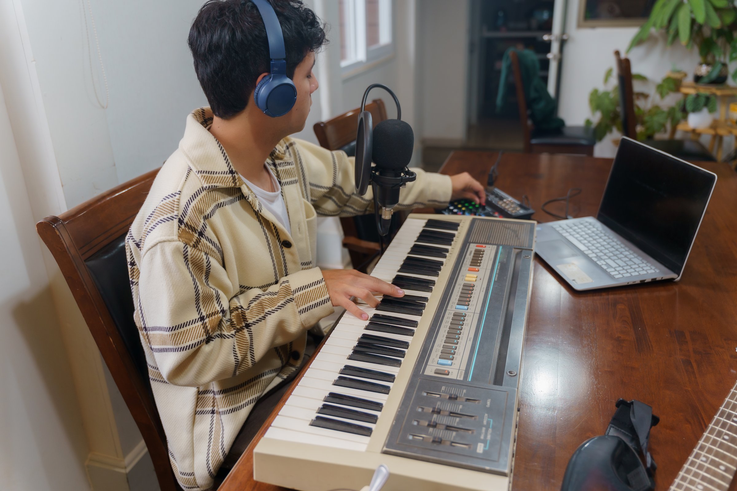 A determined and aspiring musician passionately creates vibrant music at home using a keyboard and computer