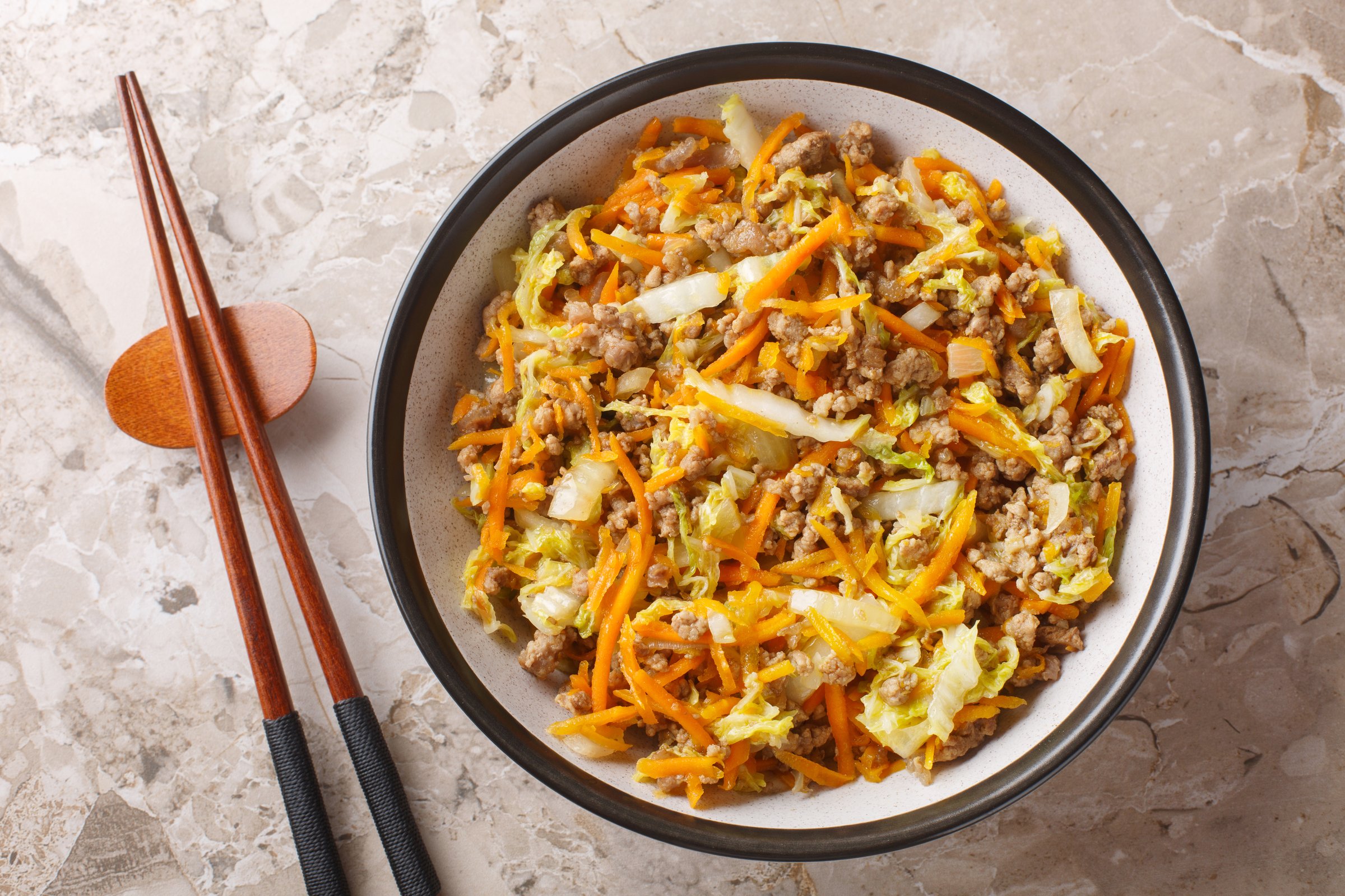 Eggroll in a bowl sauteed ground meat with vegetables in flavor packed sauce closeup on the table. Horizontal top view from above