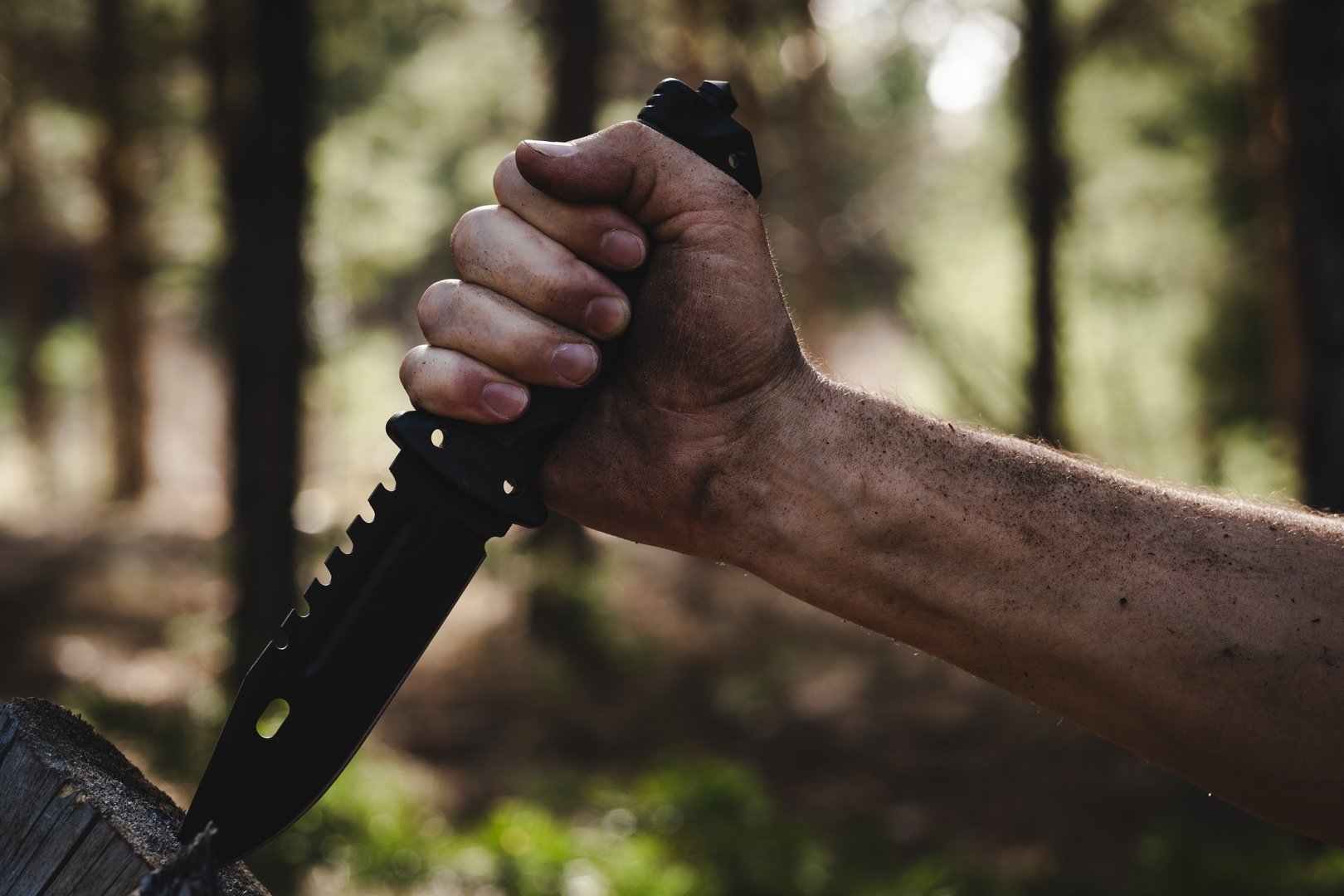 Hand of a man with a survival knife in his hands in the forest. Focus on the knife