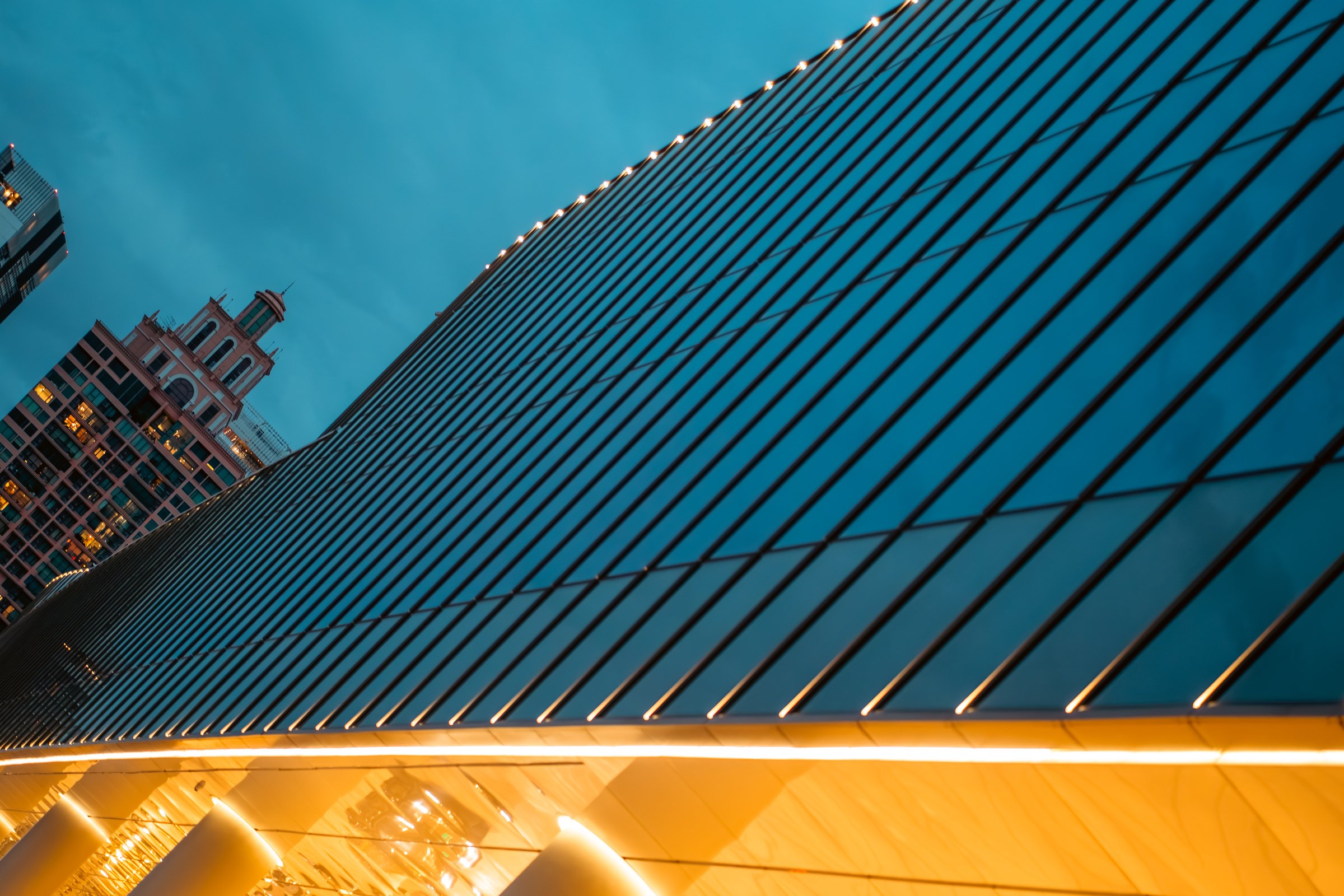 illuminated glass facade of modern skyscraper at night, sleek reflective design of contemporary high-rise building glowing. High quality photo