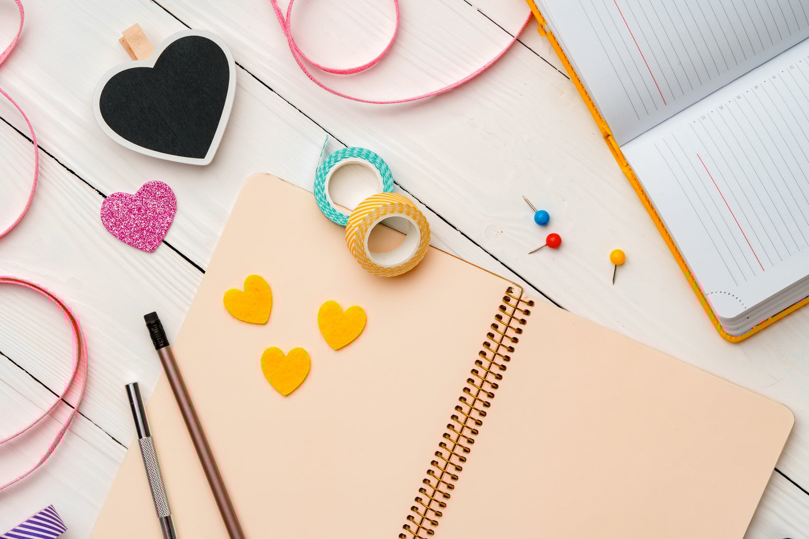 Creative workspace with colorful stationery and decorations on a white wooden desk flat lay
