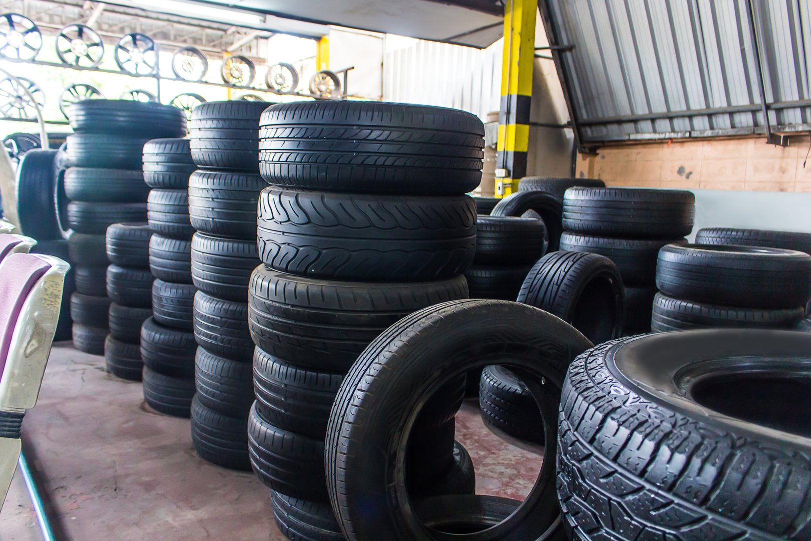 New car tire mix type at warehouse stock inventory in auto garage workshop for sale. The interior of a car tire workshop. Several black tires are arranged beautifully in the middle of the shop.