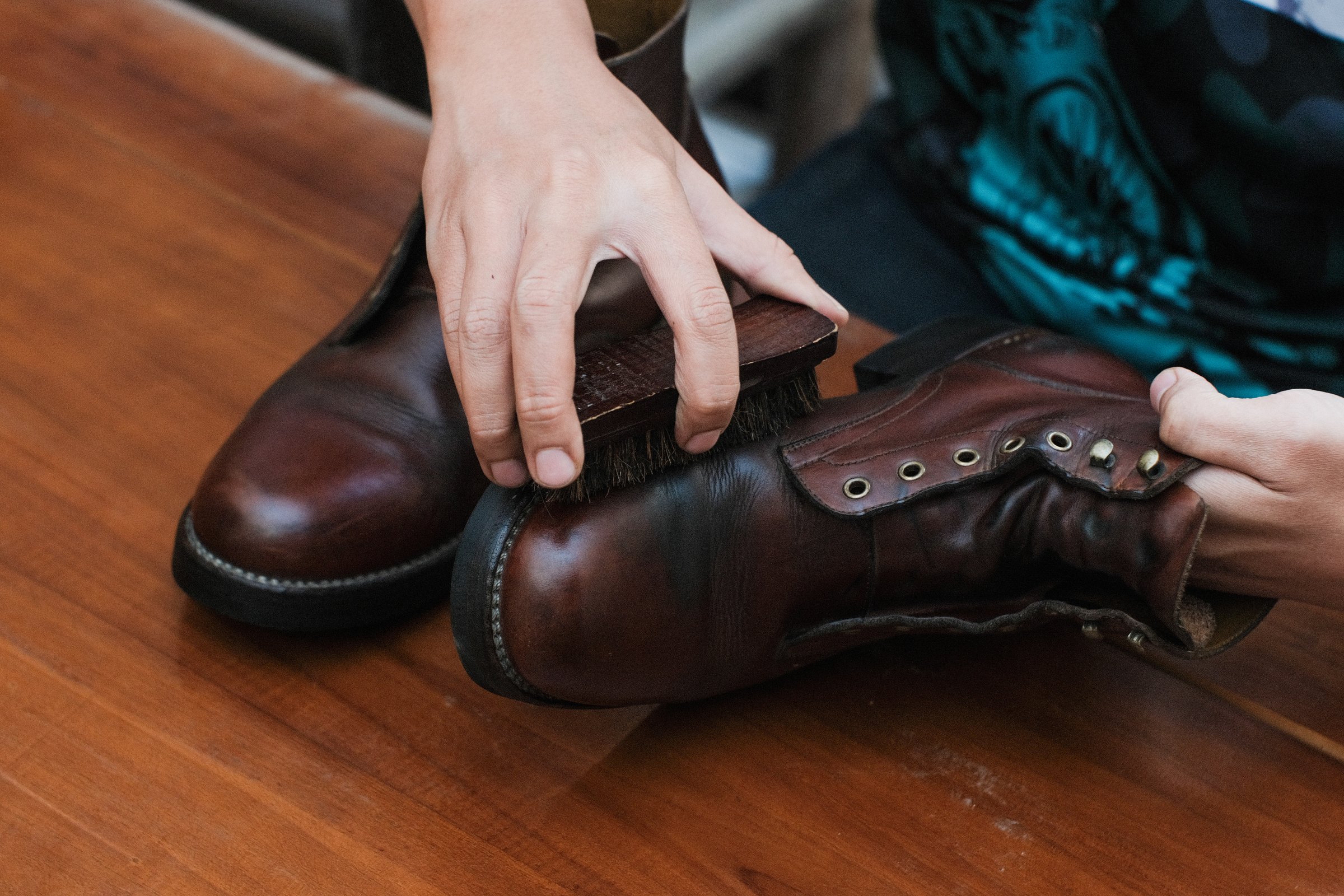Close up of a hands polishing a leather boots with brush, on wooden table, shoes shining and cleaning.