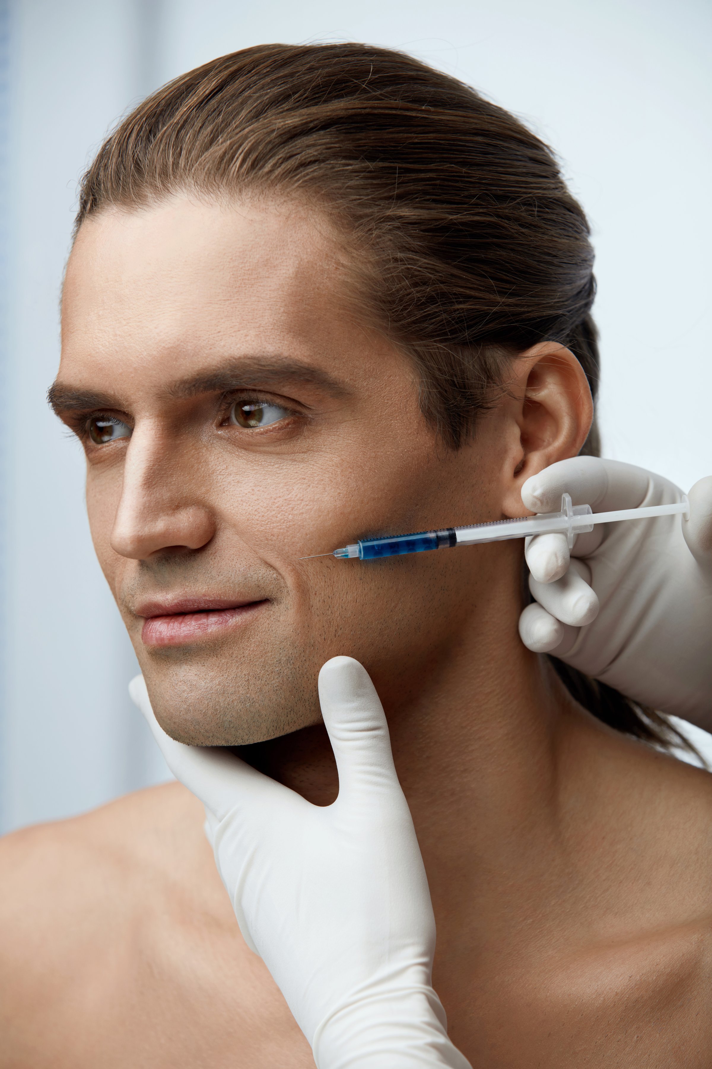 Beauty Injection. Portrait Of Handsome Sexy Man Getting Face Lifting Procedure On White Background. Close Up Doctor Hands Injecting Fillers Into Male Facial Skin. Cosmetology Concept. High Resolution