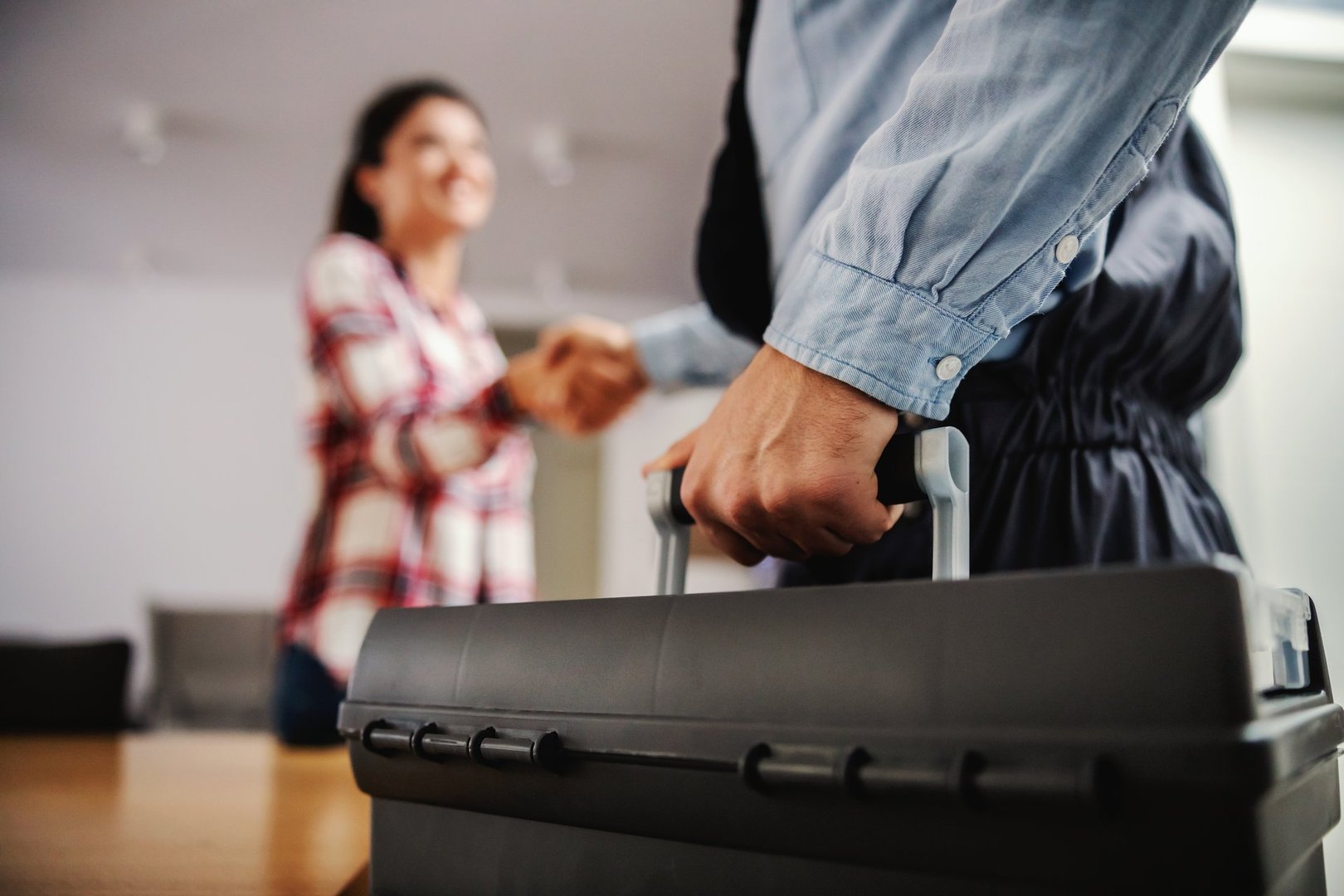 Woman shaking hands with a repairman while standing at home.