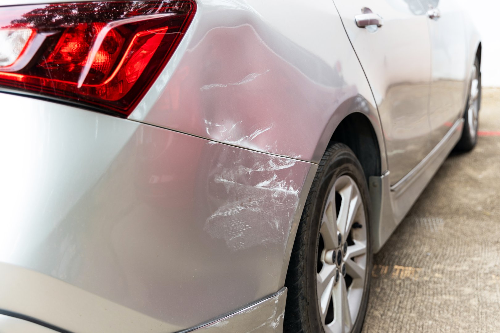 Dreaded scratch down the side car get damaged from accident on the road. Vehicle bumper dent and taillight broken by car crash. Road accidents and car insurance or scratch remover product business concept.