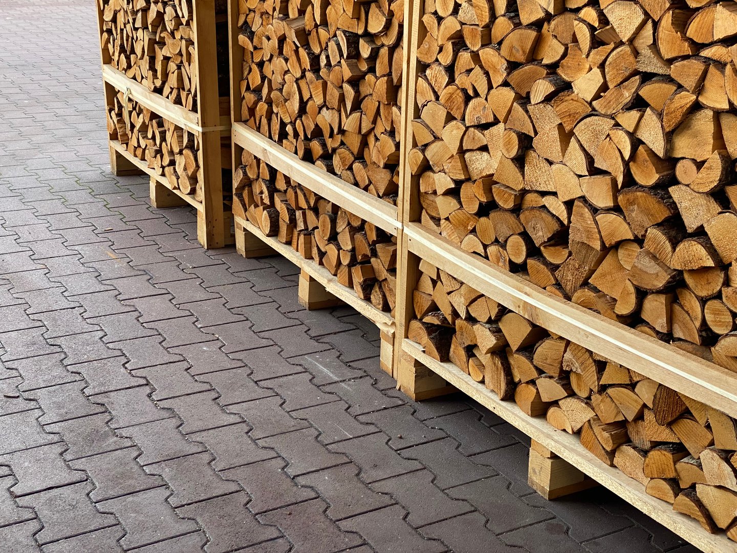 stacked firewood on pallets on paved surface