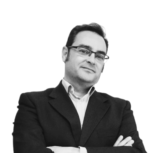 Man in a suit with glasses, arms crossed, posing confidently against a plain white background.