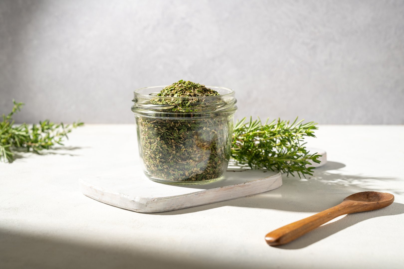 Mix of dried green herbs spice in a glass jar