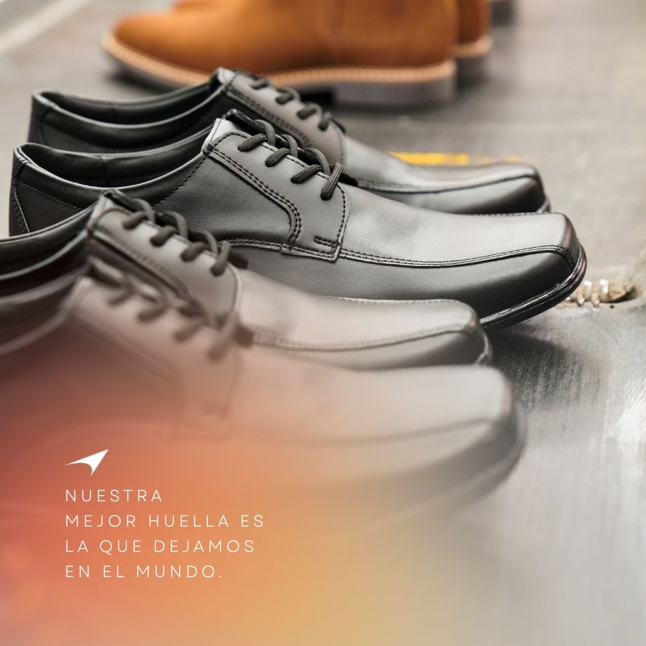 Row of black leather shoes on display with Spanish text about making an impact. Brown shoe blurred in the background.