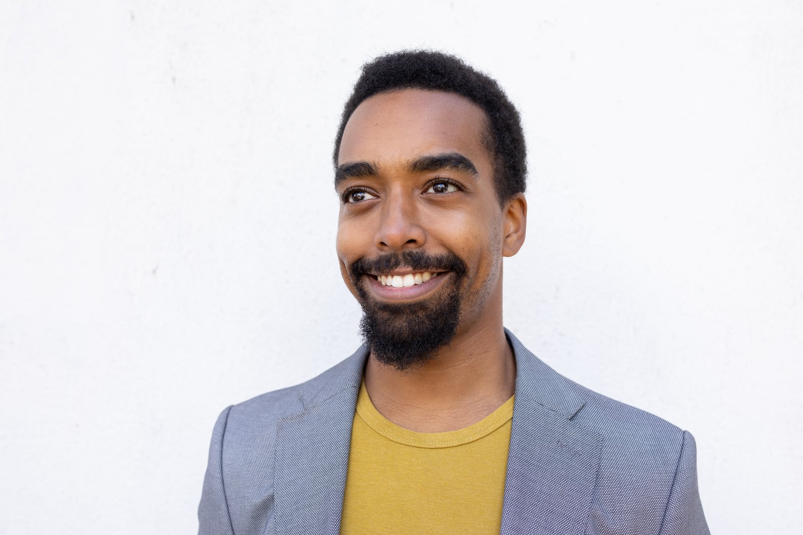 Cheerful young businessman smiling confidently, gazing upward with optimistic expression