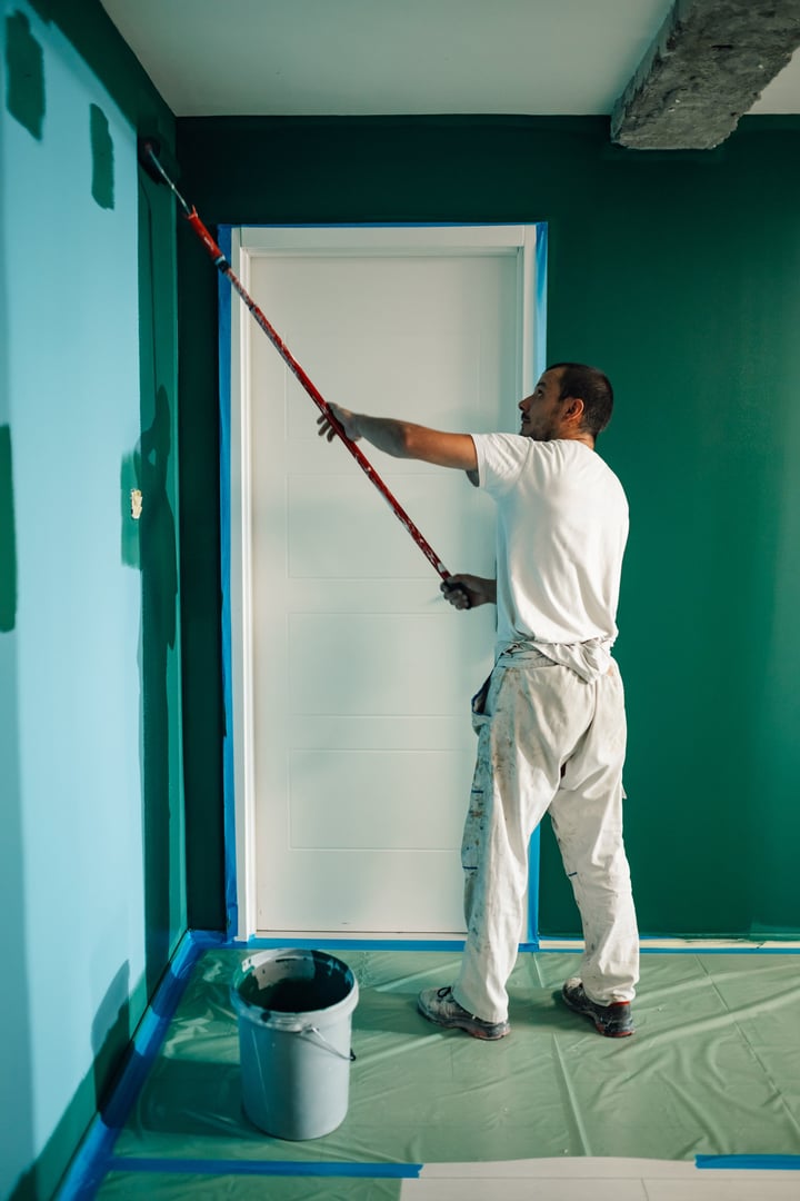 Painter applying vibrant green paint on a wall, transforming the space during a home renovation project and enhancing interior decor