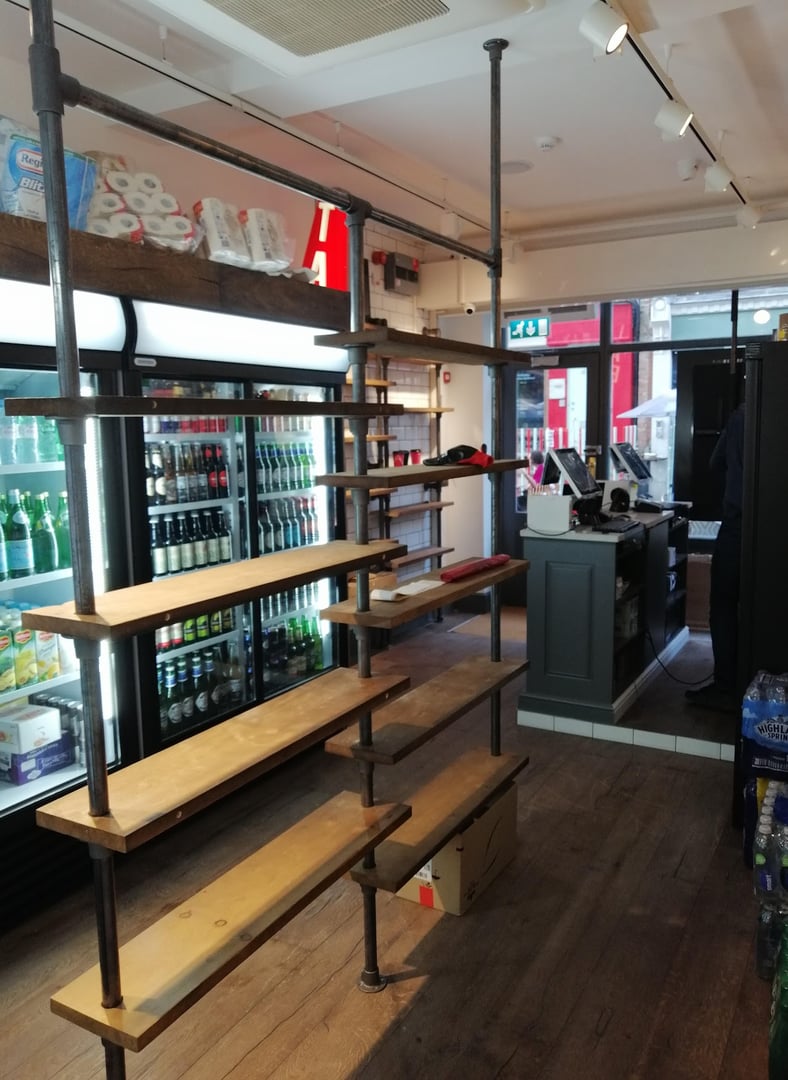 A bathroom with a blue and gold pattern wallpaper, gold faucet and light fixtures, and a white cabinet and sink.