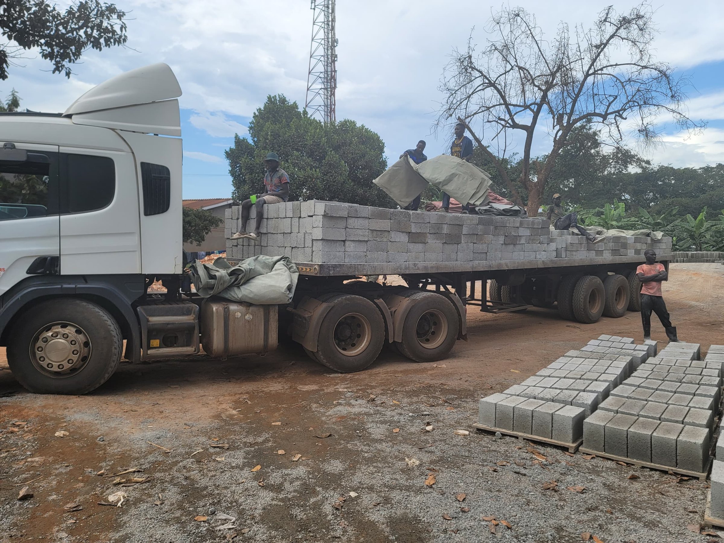 Workers unloading concrete blocks from a flatbed truck in an outdoor setting.
