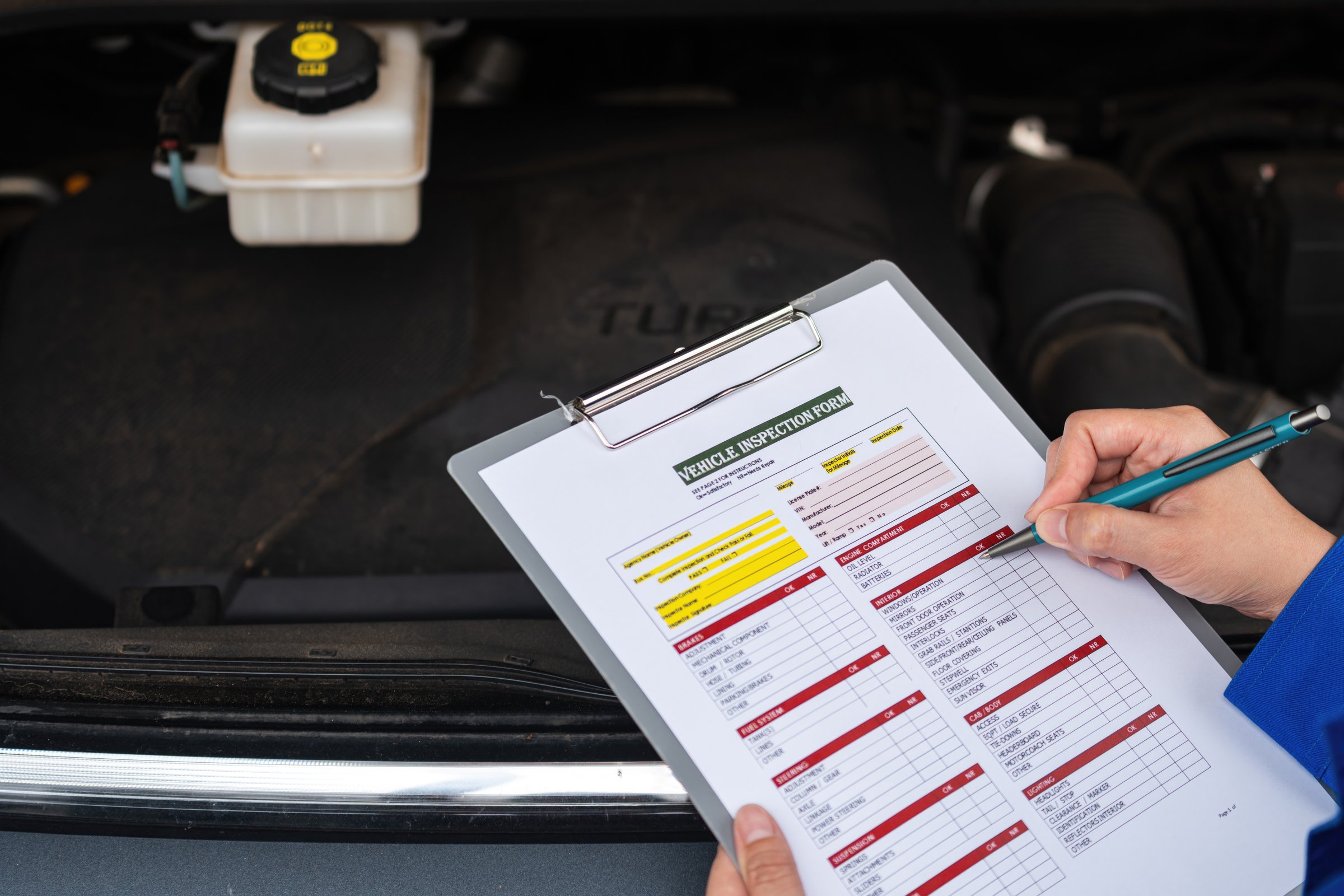 Action of a car service technician is checking on vehicle inspection checklist form during perform the maintenance job