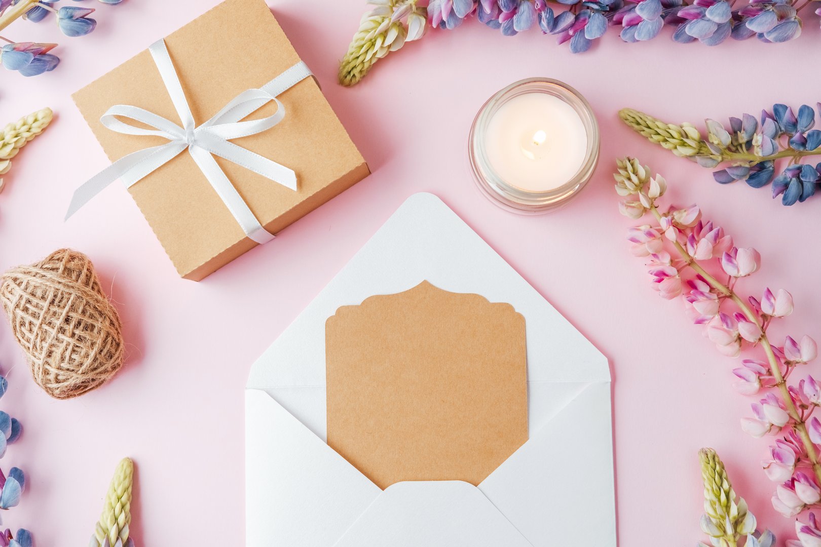 Gift box and envelope with card and flowers on pink background