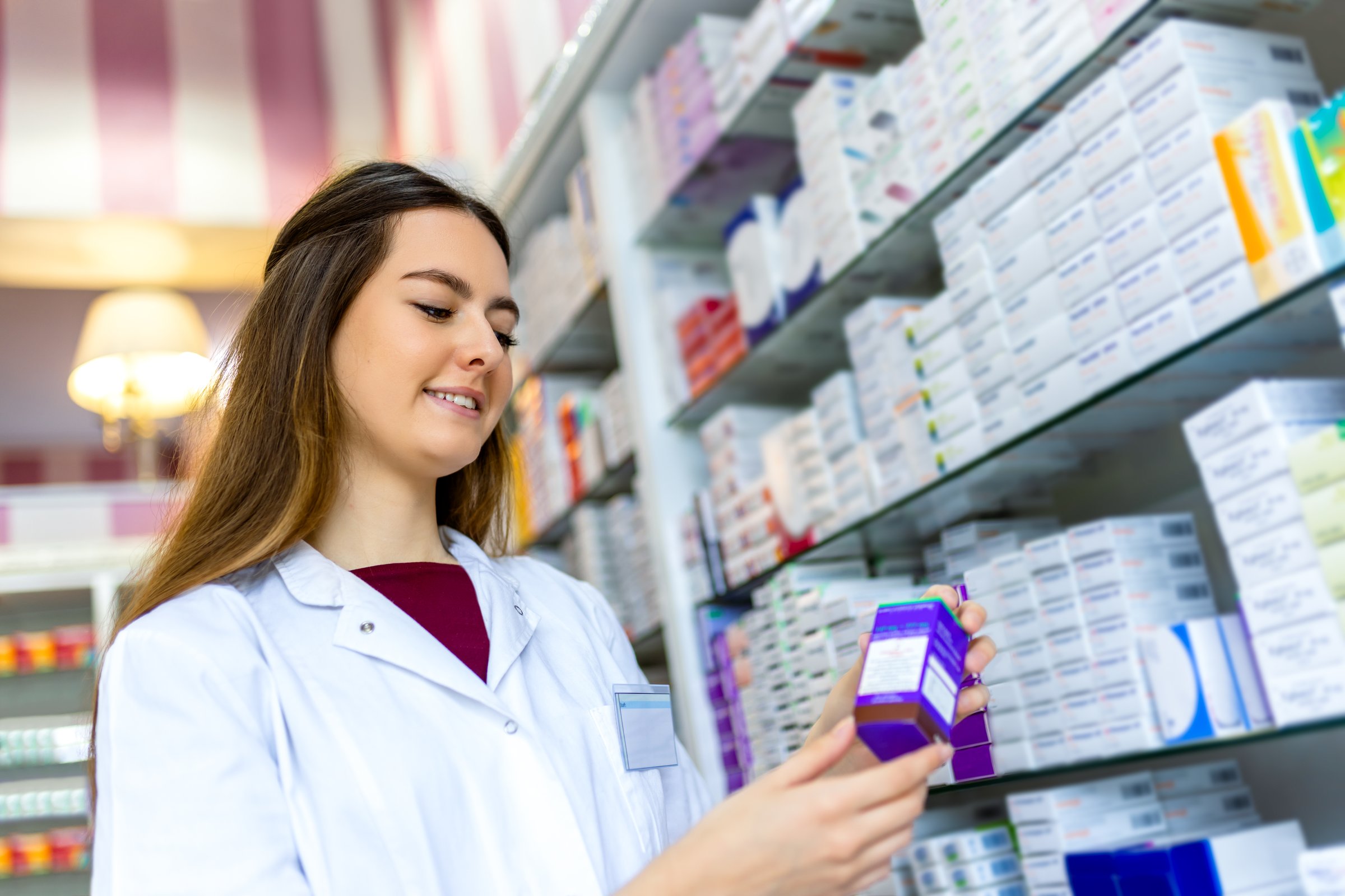 Pharmacy inventory check. Woman checks for medicine on the shelf. Following the checklist.
