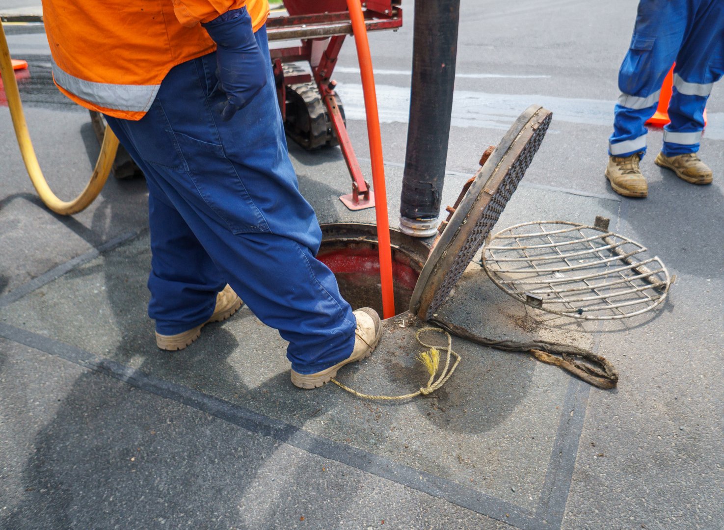Workers cleaning and unblocking sewers on street. Auckland.