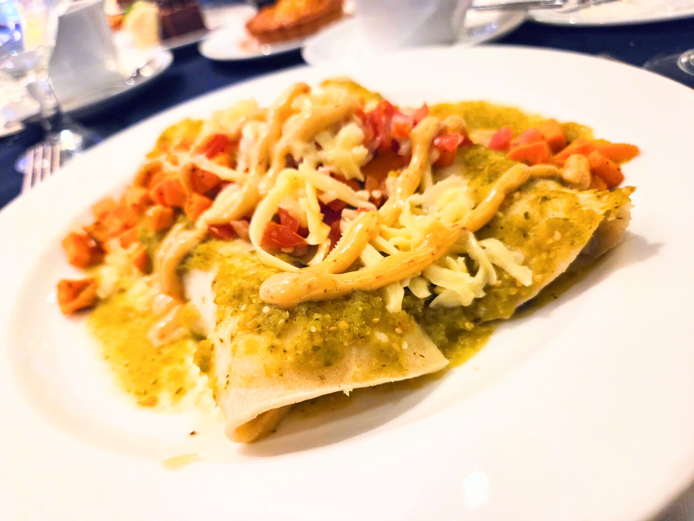 Closeup of an enchilada covered in sauce made from vegetables.