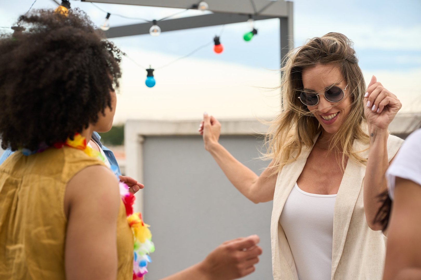 Group of friends celebrating on a rooftop, dancing joyfully and enjoying each other's company under the vibrant city lights