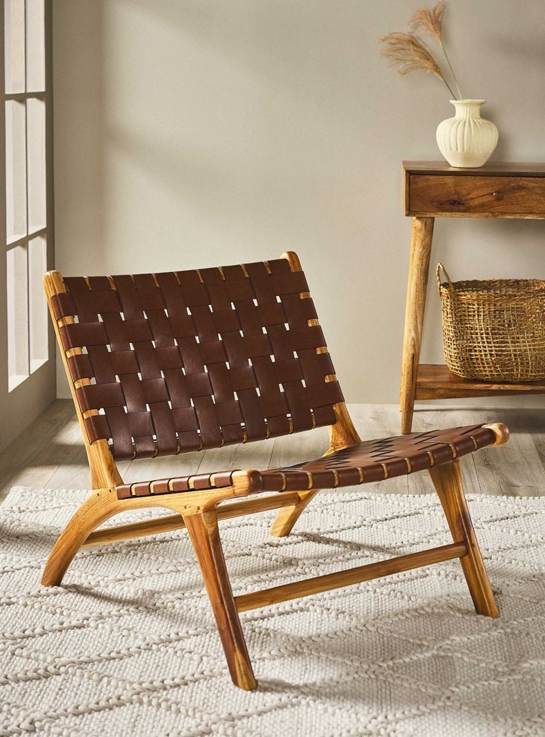 Sillón lounge con entramado de tiras de piel en patrón cruzado y estructura de parota con líneas curvas