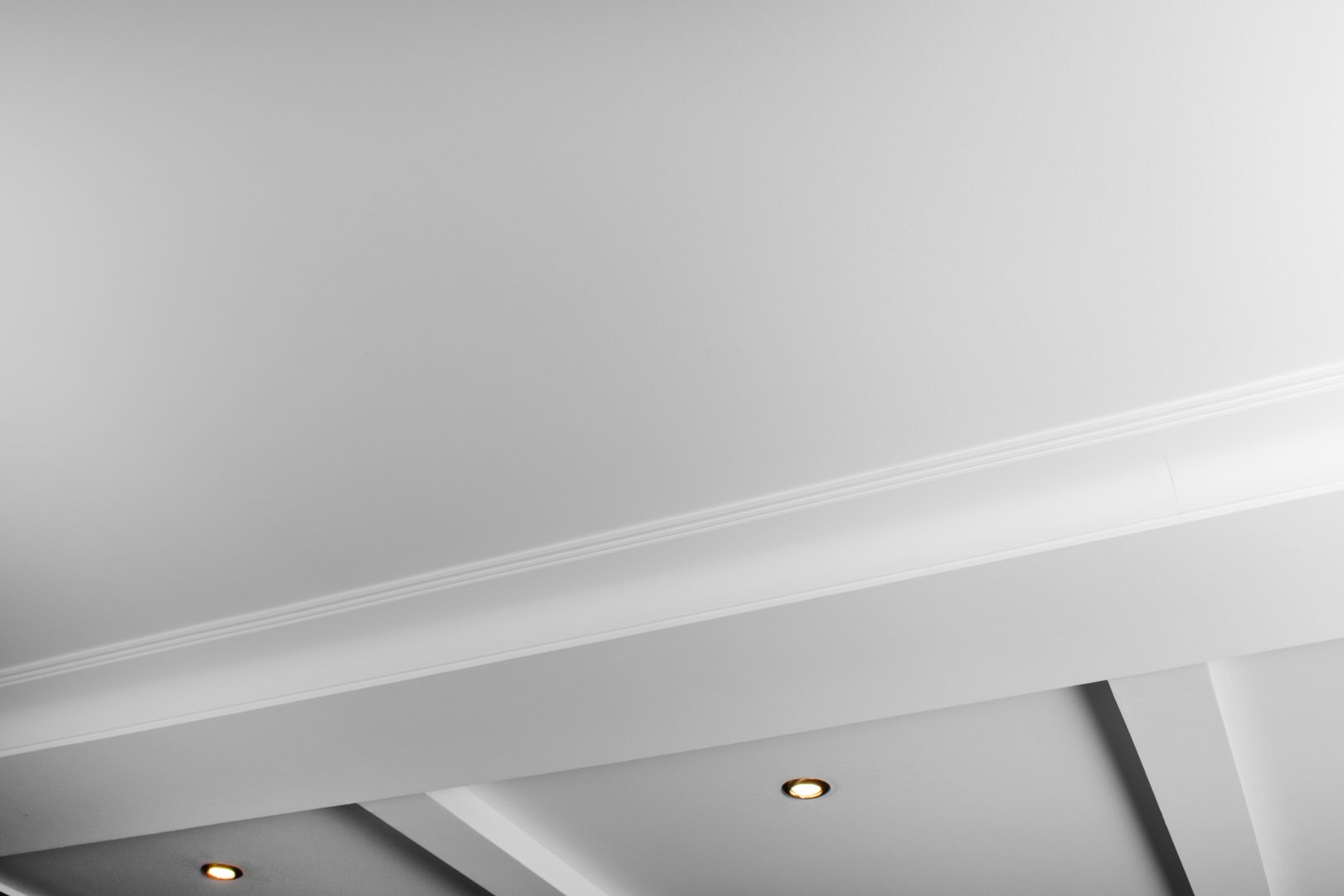 Suspended and grid ceiling with LED spots lamps and drywall construction in empty room in house interior. Stretch ceiling white and complex shape.