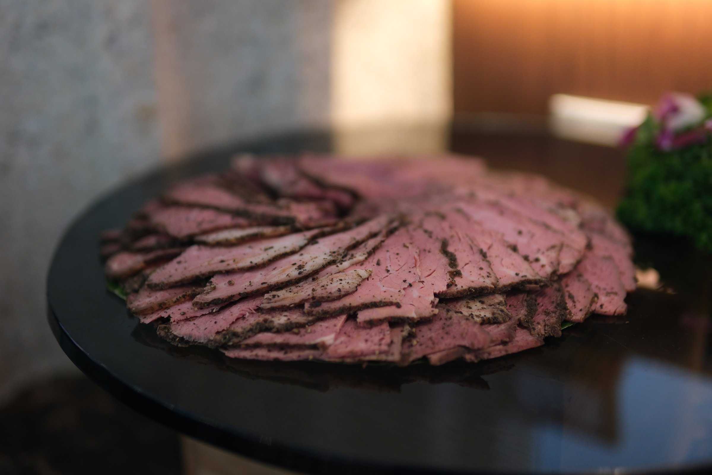Caucasian man hand puts plastic package with circles of thinly sliced ham on table. Plastic packaging for chopped snacks on stone. Sliced into thin pieces of ham on cutting serving board.