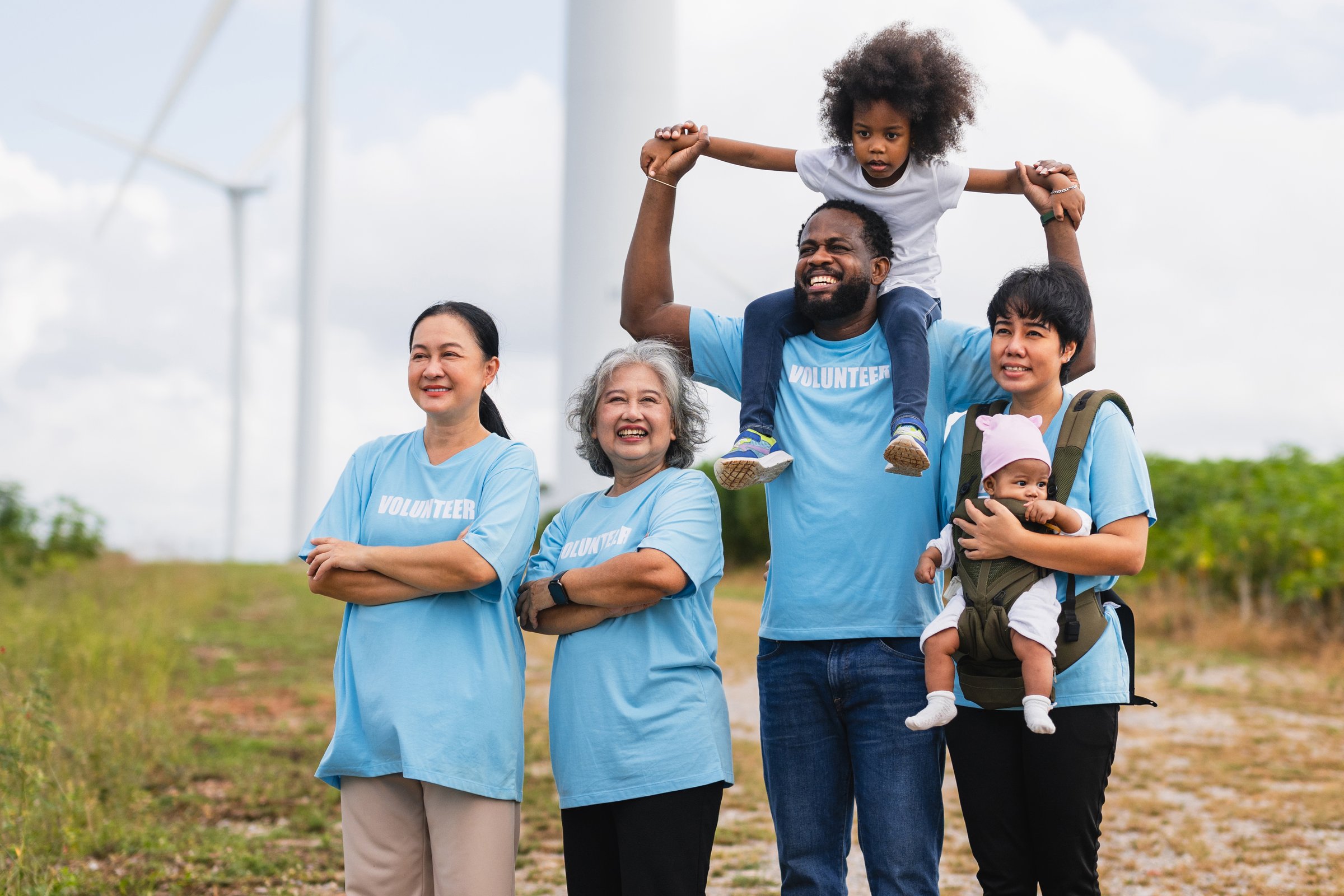 group of people wearing blue shirts with the word volunteer on them. They are smiling and holding a baby