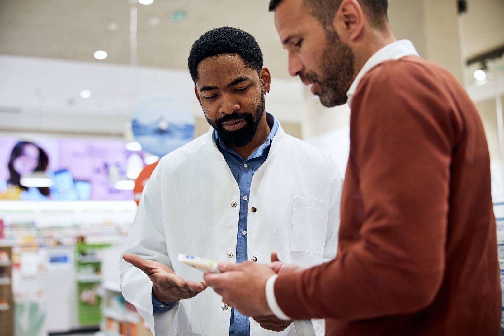 Pharmacist explaining a product to a customer in a clean and professional pharmacy.