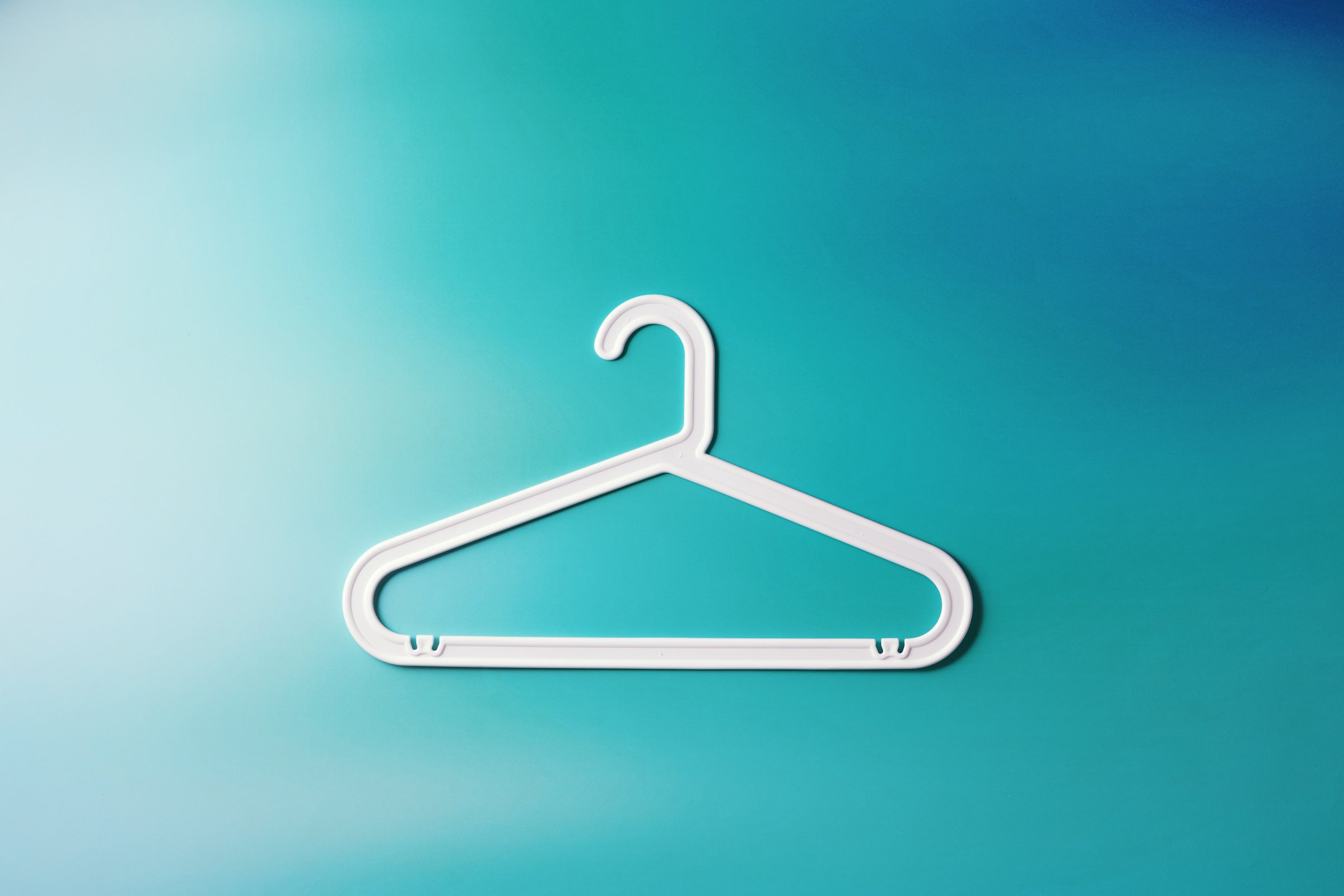 Top view White Plastic hanger, minimal style layout on white teal gradient background, Clothes rack for organizing clothes in closets or retail stores, fashion, organization concept, copy space