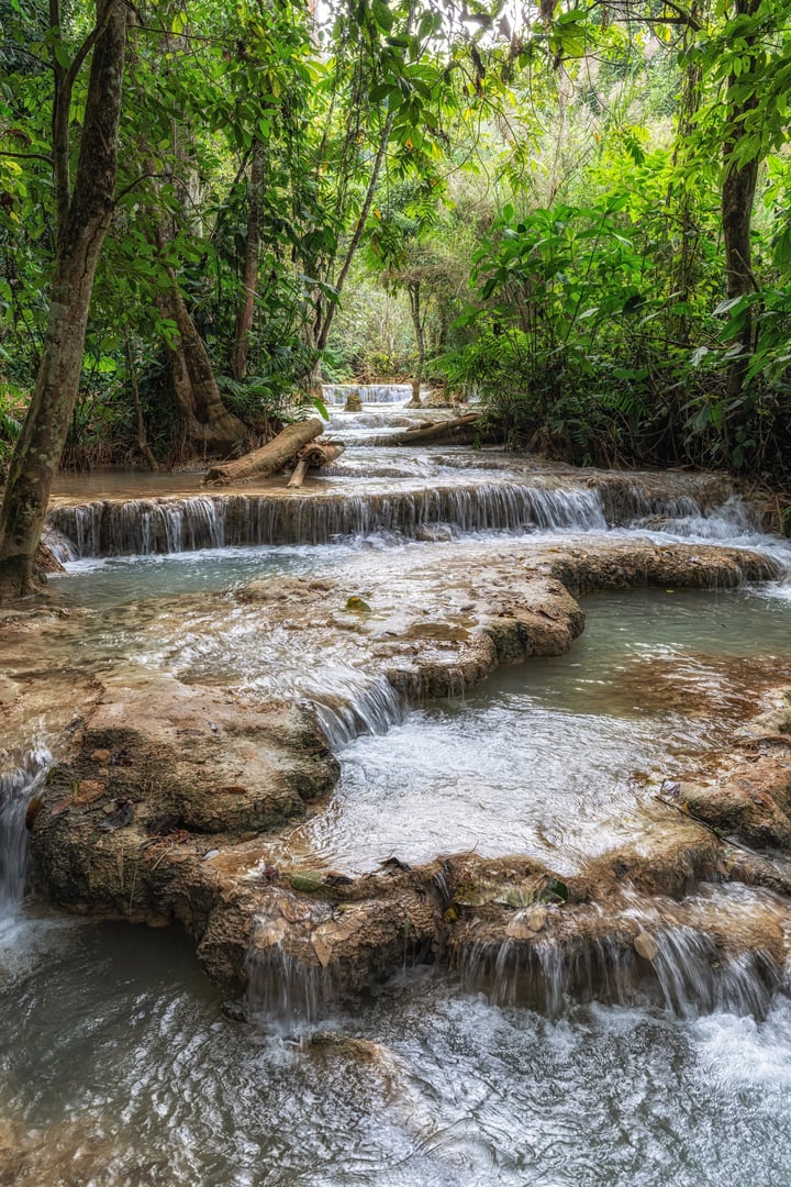 Various views of turquoise colored waterpools and waterfalls surrounded by lush forest. Taken in Kuang Si Waterfalls in Luang Prabang, Laos