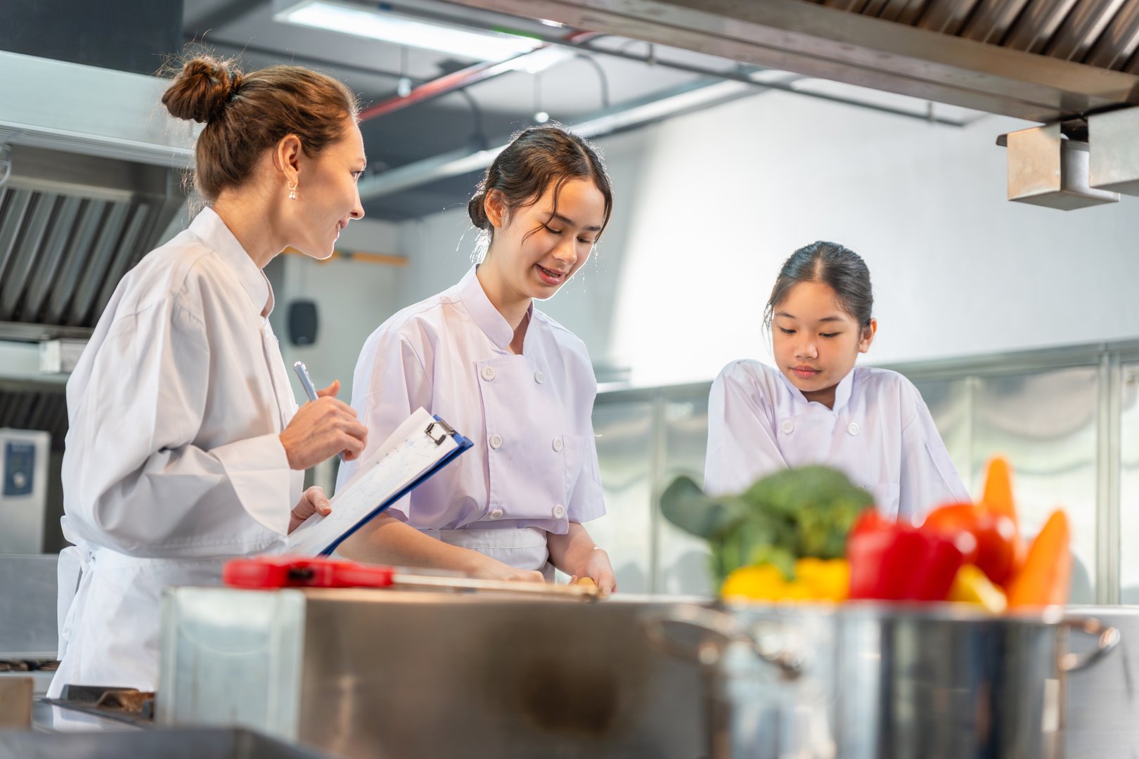 Teacher and student in cooking class, Young chefs learning to cook with an instructor