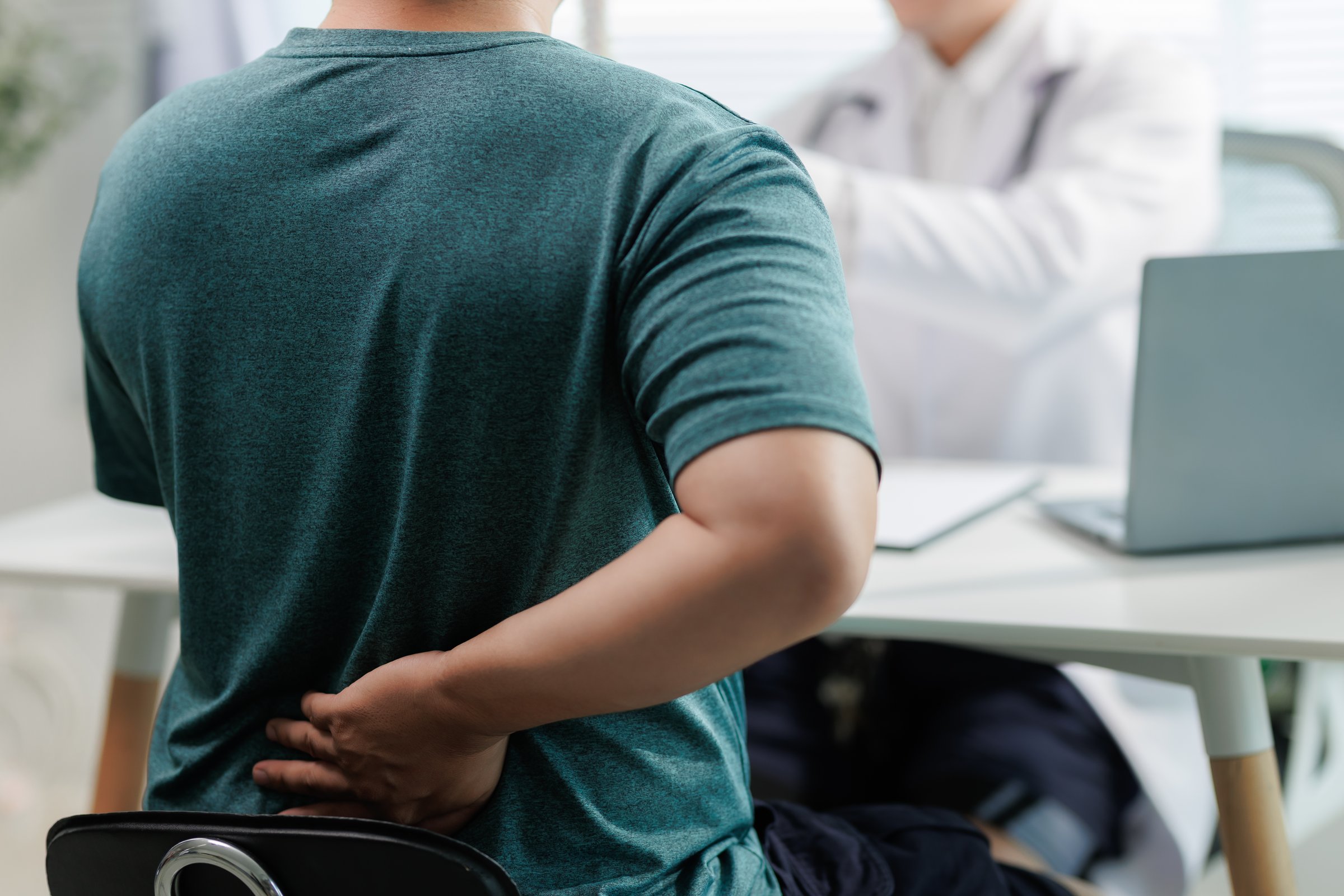 Patient consulting doctor about chronic back pain.
