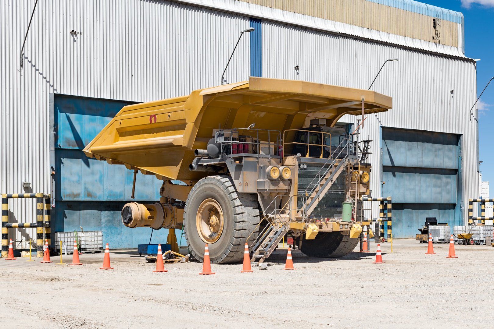 Mining truck in maintenance workshop with giant tire removed