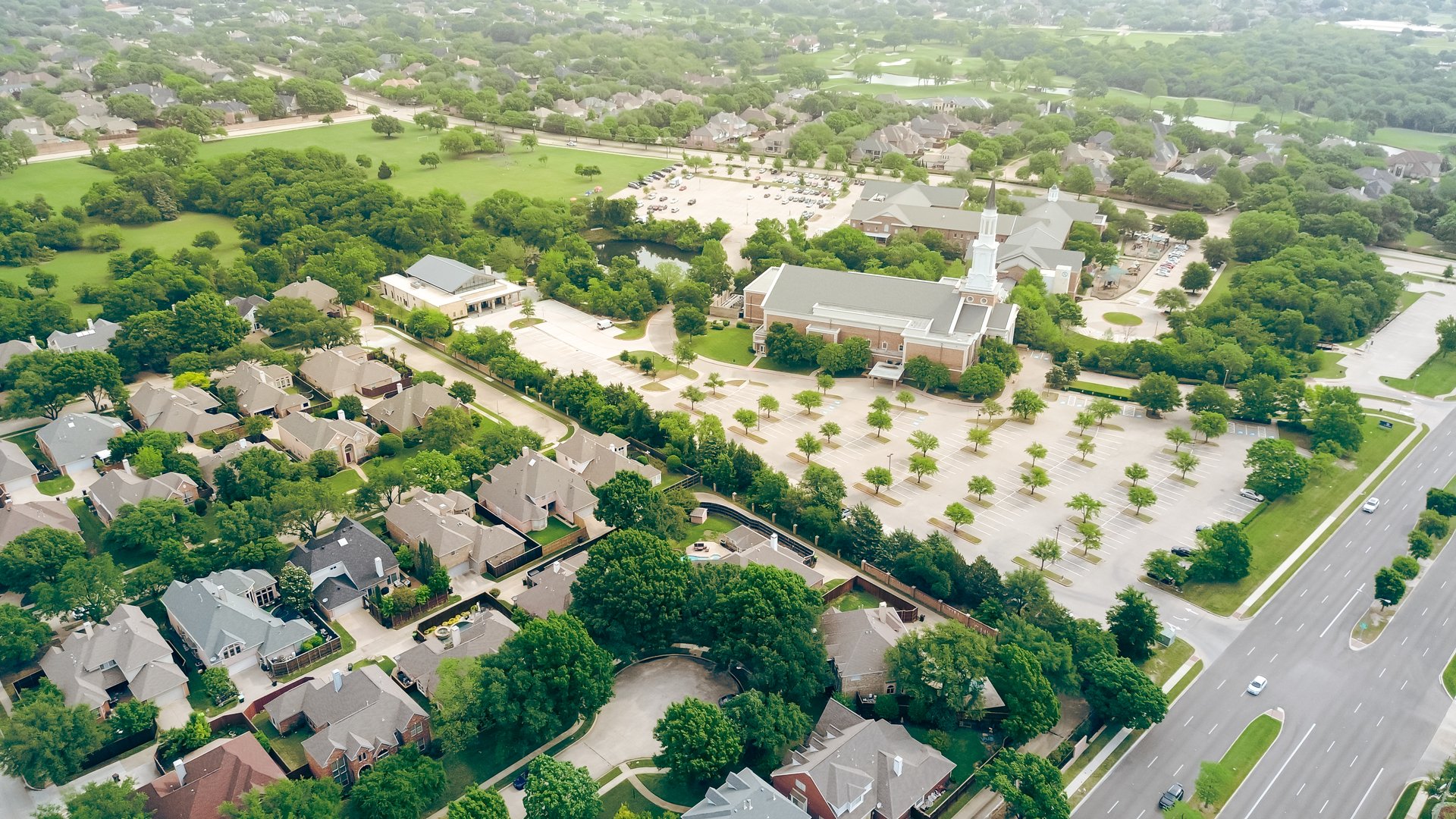 Large church in master planned community with park, country club, row of two-story houses along West Plano Parkway, upscale neighborhood green space in rapid growing suburbs Dallas metroplex. USA