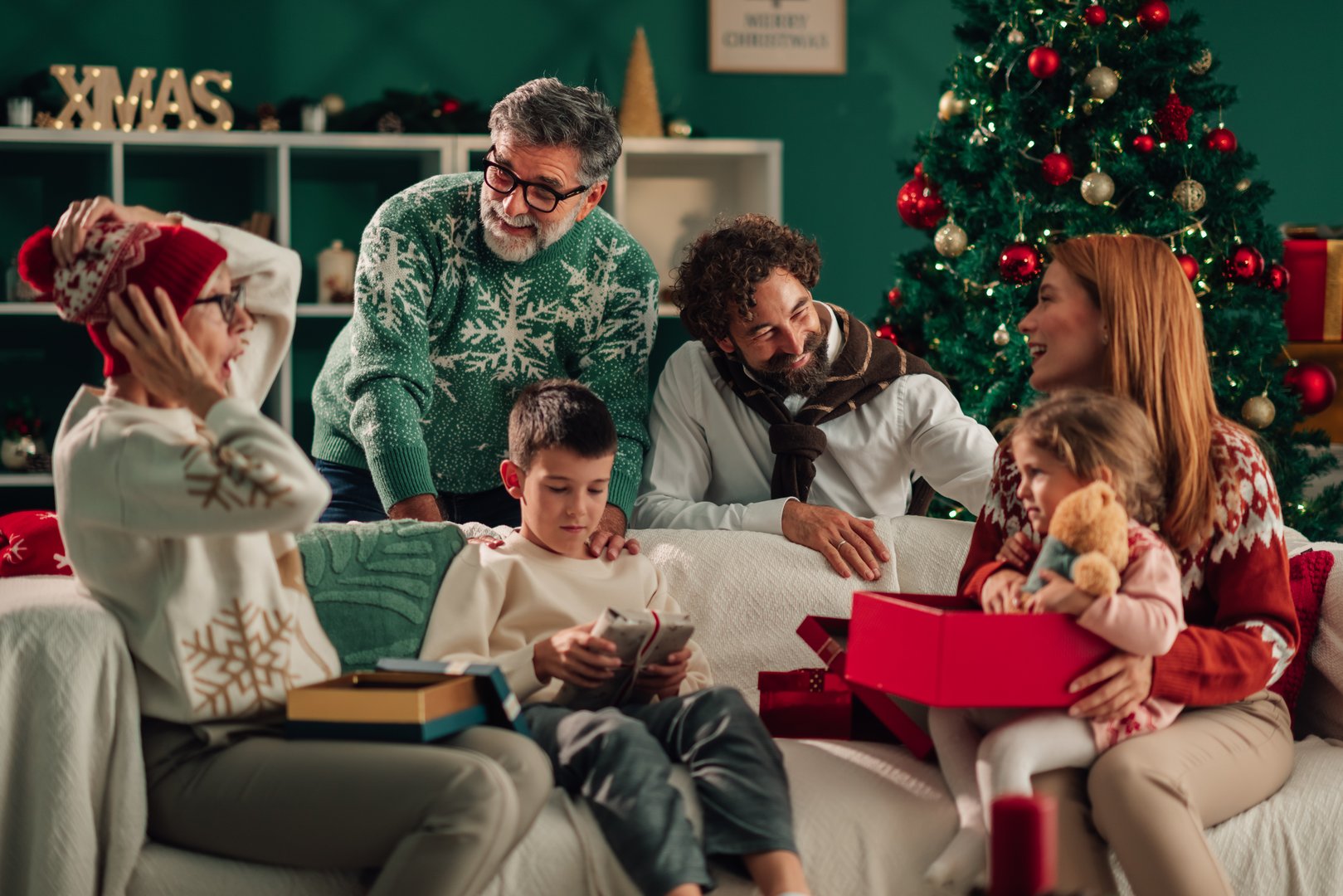 Happy family exchanging christmas gifts while sitting together on a cozy sofa in the living room, radiating joy and warmth