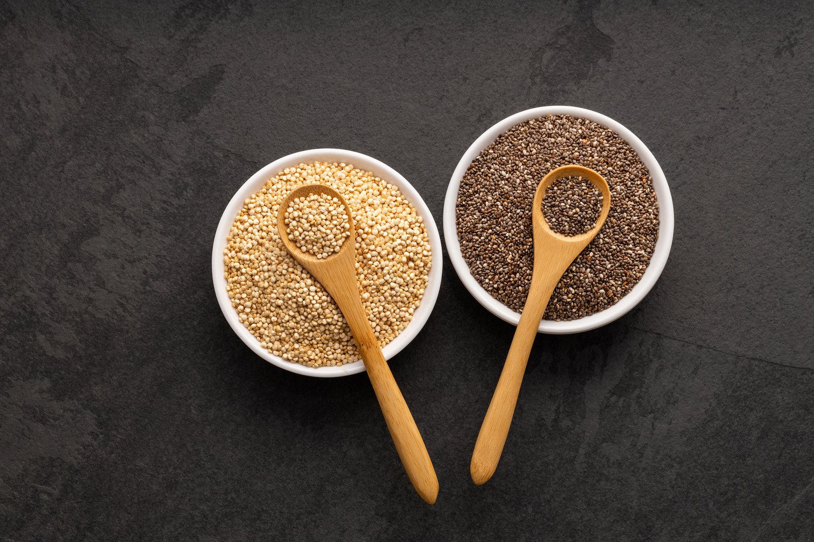 Flax and chia seeds in two spoons and two bowls - Salvia hispanica and Chenopodium quinoa.