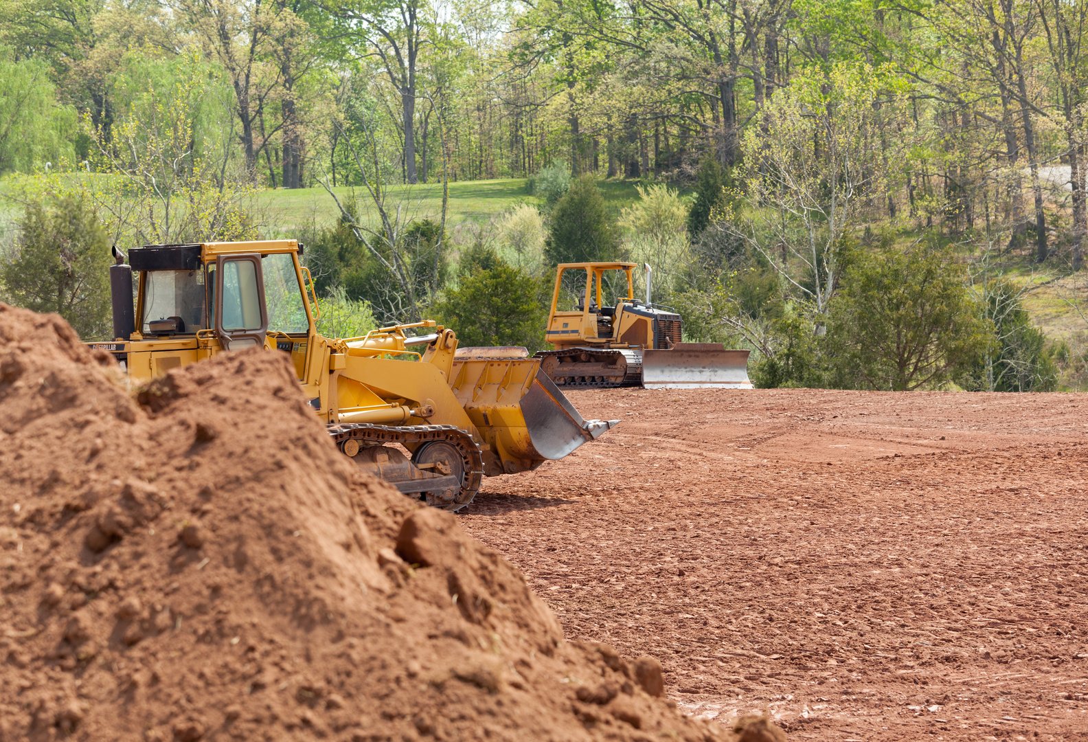 Land being levelled and cleared by yellow earth moving digger