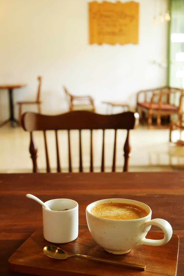 Cup of hot coffee with sugar pot being served on cafe's wooden table