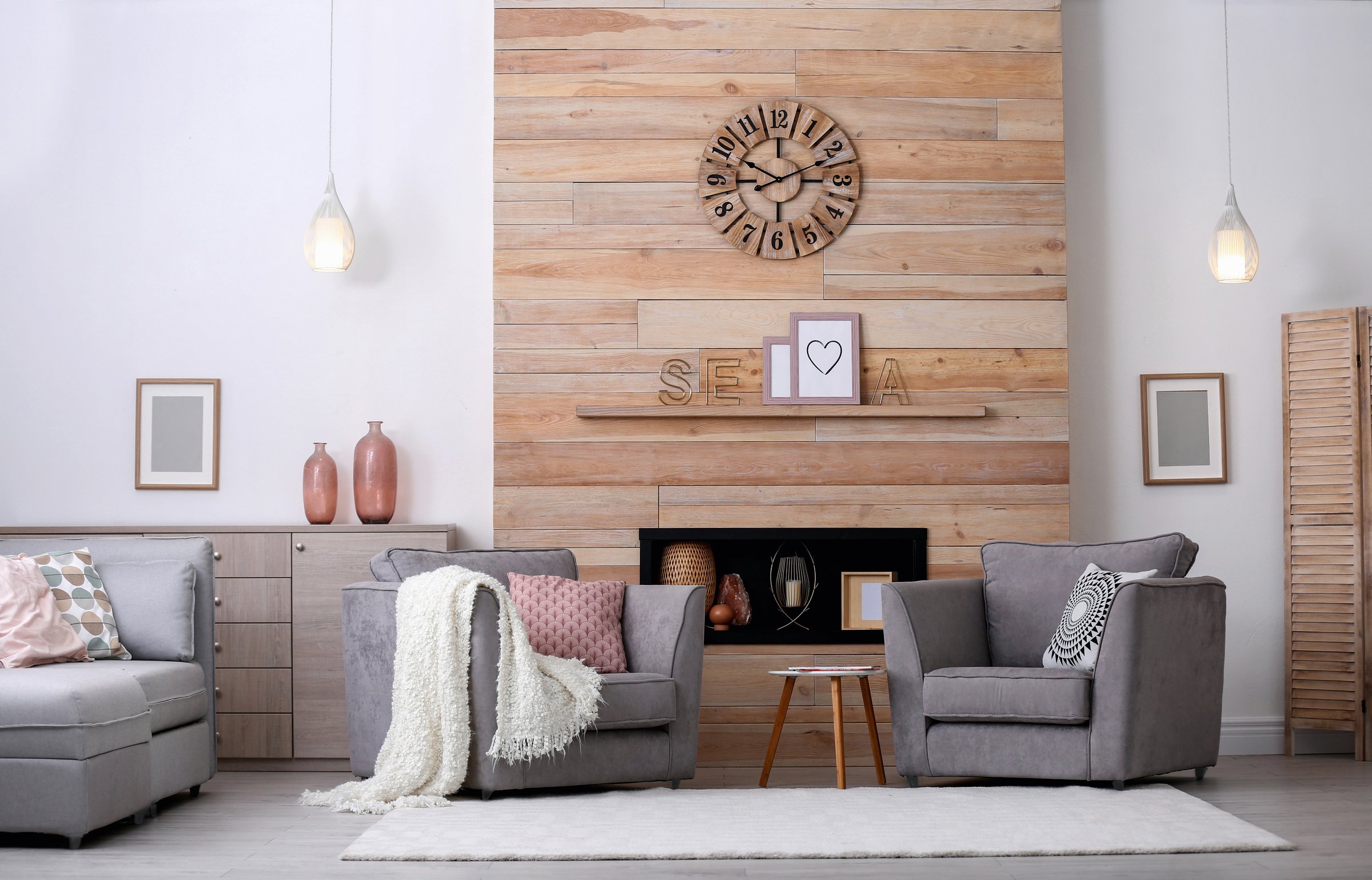 Spacious and comfortable modern living room interior design featuring large gray seating furniture. The accent wall is clad in natural wooden planks with a clock centerpiece above a recessed fireplace, perfect for home decor inspiration.