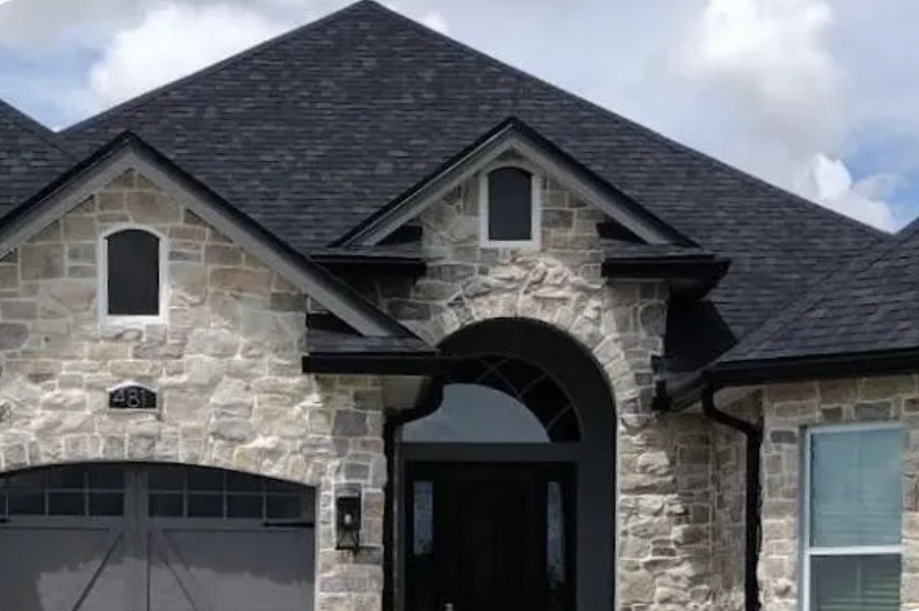 Exterior view of a contemporary home highlighting a sleek black gutter along the roofline under a bright blue sky.