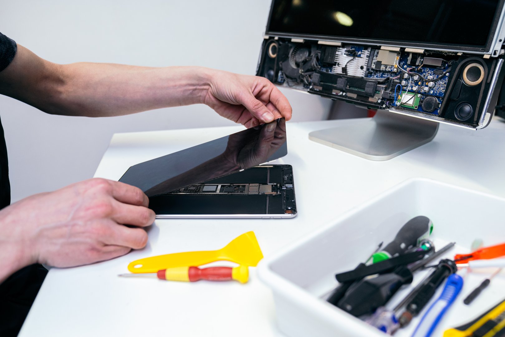 Peeling back the screen of a tablet for repair.