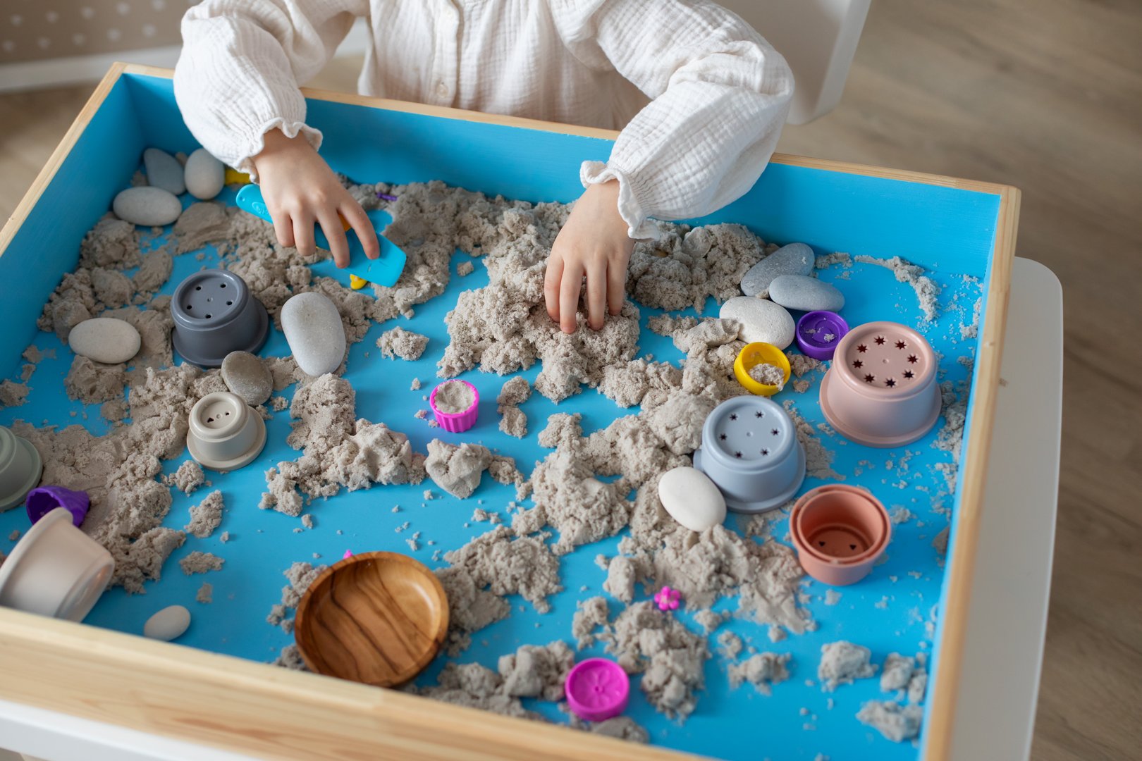 Children activity with kinetic sand for motor and sensory development. Toddler play therapy with colorful toys on sandbox.